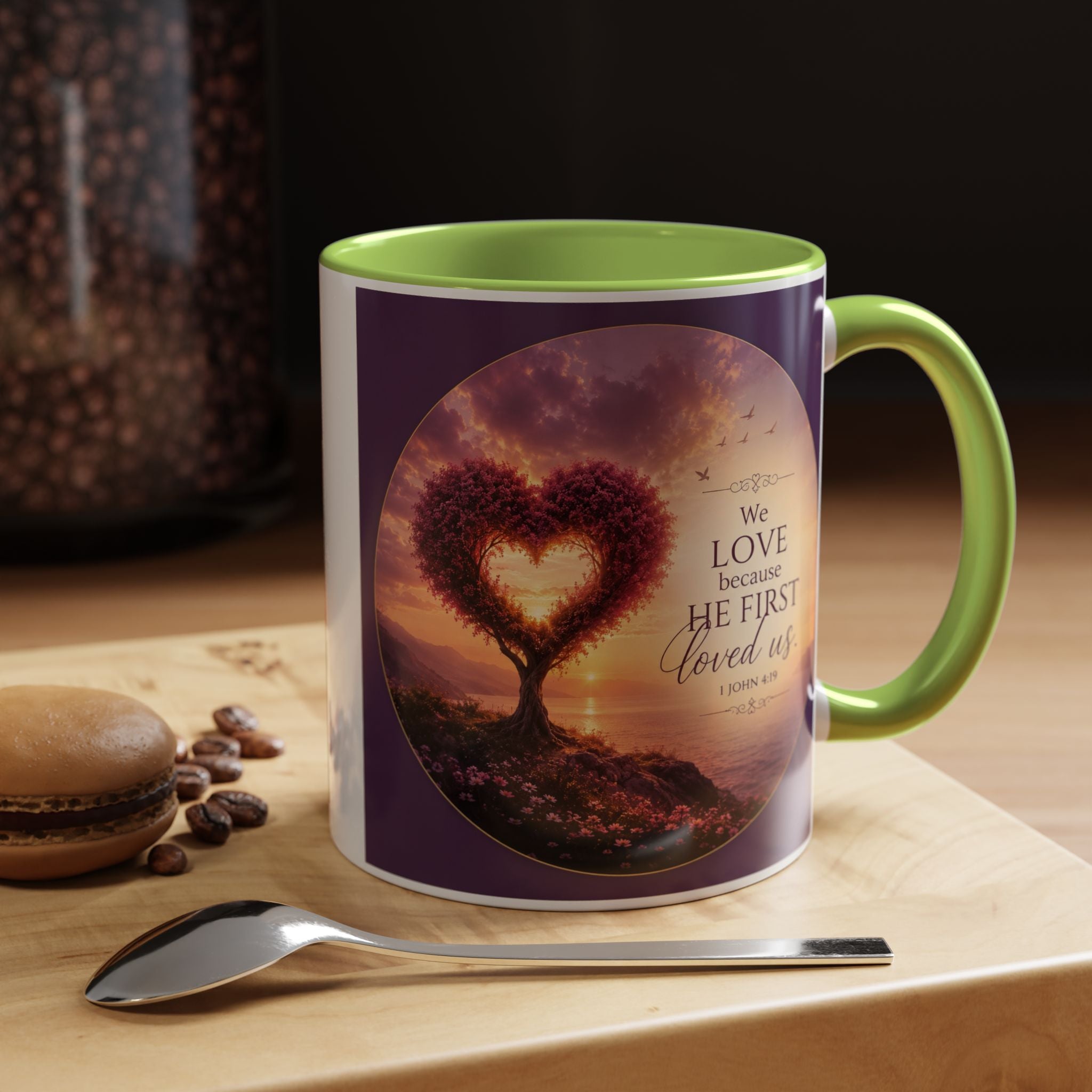 Inspirational Christian coffee mug featuring a glowing heart-shaped tree at sunset with the scripture “We Love Because He First Loved Us” from 1 John 4:19 and contrasting black handle and interior.