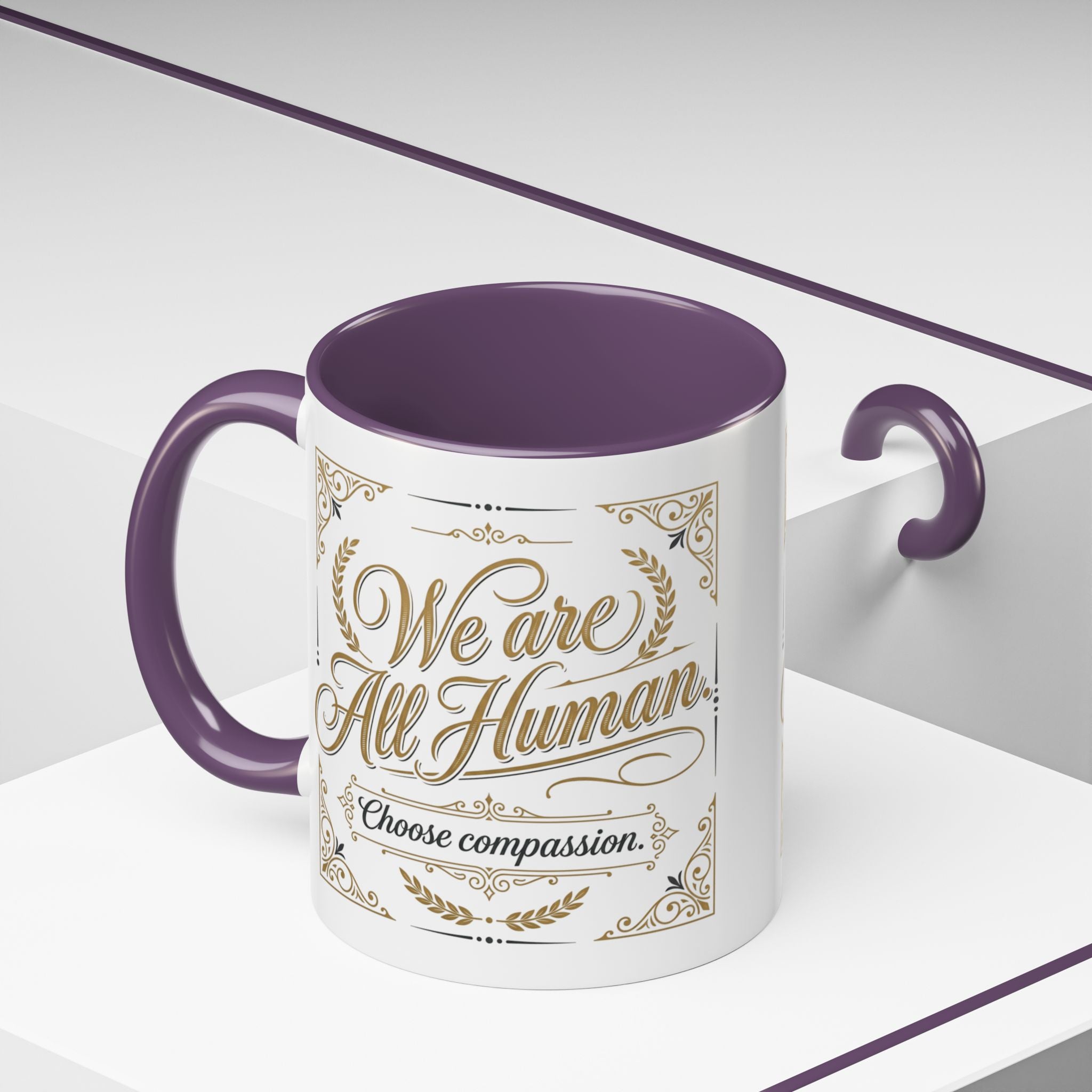 Inspirational ceramic accent coffee mug featuring “We Are All Human – Choose Compassion” in vintage-style gold lettering with decorative flourishes and black accent handle and interior.