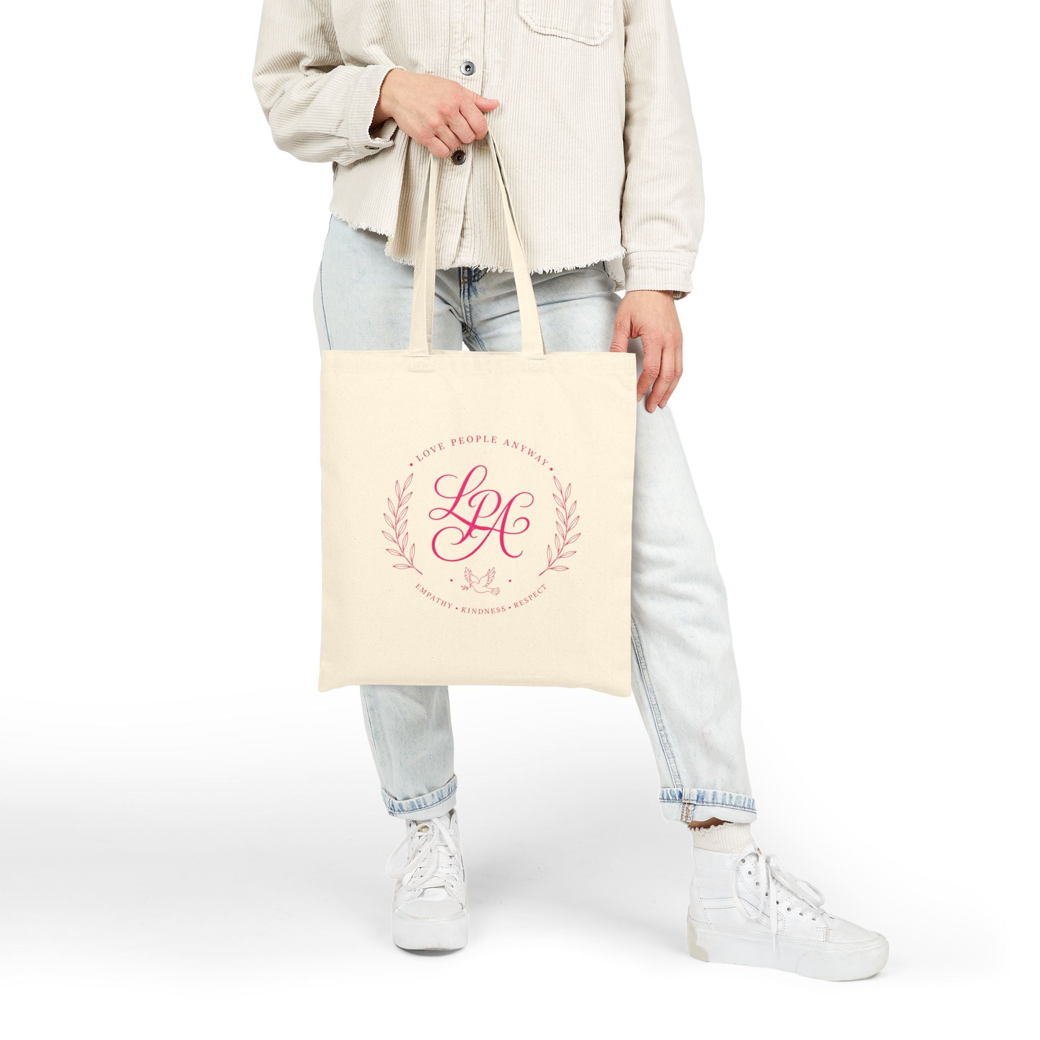 Pink monogram cotton canvas tote bag featuring the message “Love People Anyway,” laurel branches, a dove carrying an olive branch, and the words empathy, kindness, and respect in an elegant boutique design.