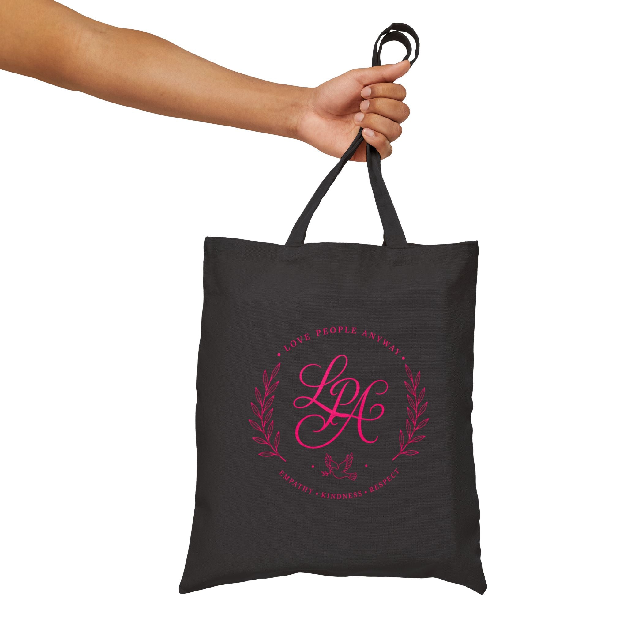 Pink monogram cotton canvas tote bag featuring the message “Love People Anyway,” laurel branches, a dove carrying an olive branch, and the words empathy, kindness, and respect in an elegant boutique design.