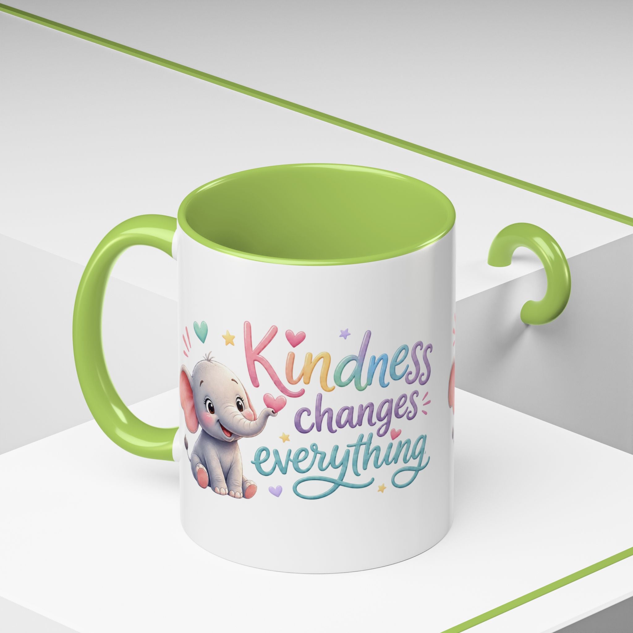 Cute ceramic coffee mug featuring a pastel baby elephant and the uplifting message “Kindness Changes Everything” with colorful accent handle and interior.