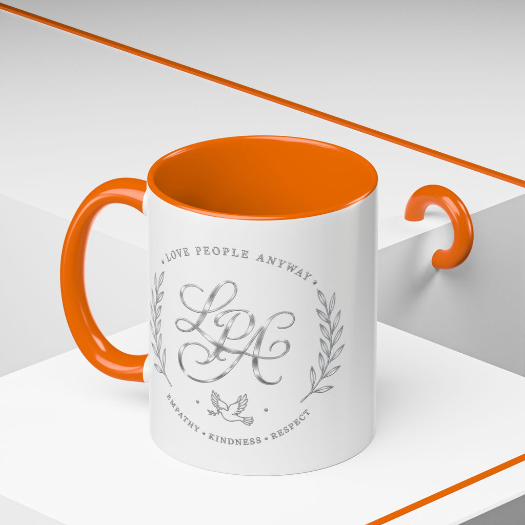 Inspirational ceramic coffee mug featuring silver “Love People Anyway” script, elegant monogram styling, decorative wreath accents, and contrasting handle and interior.