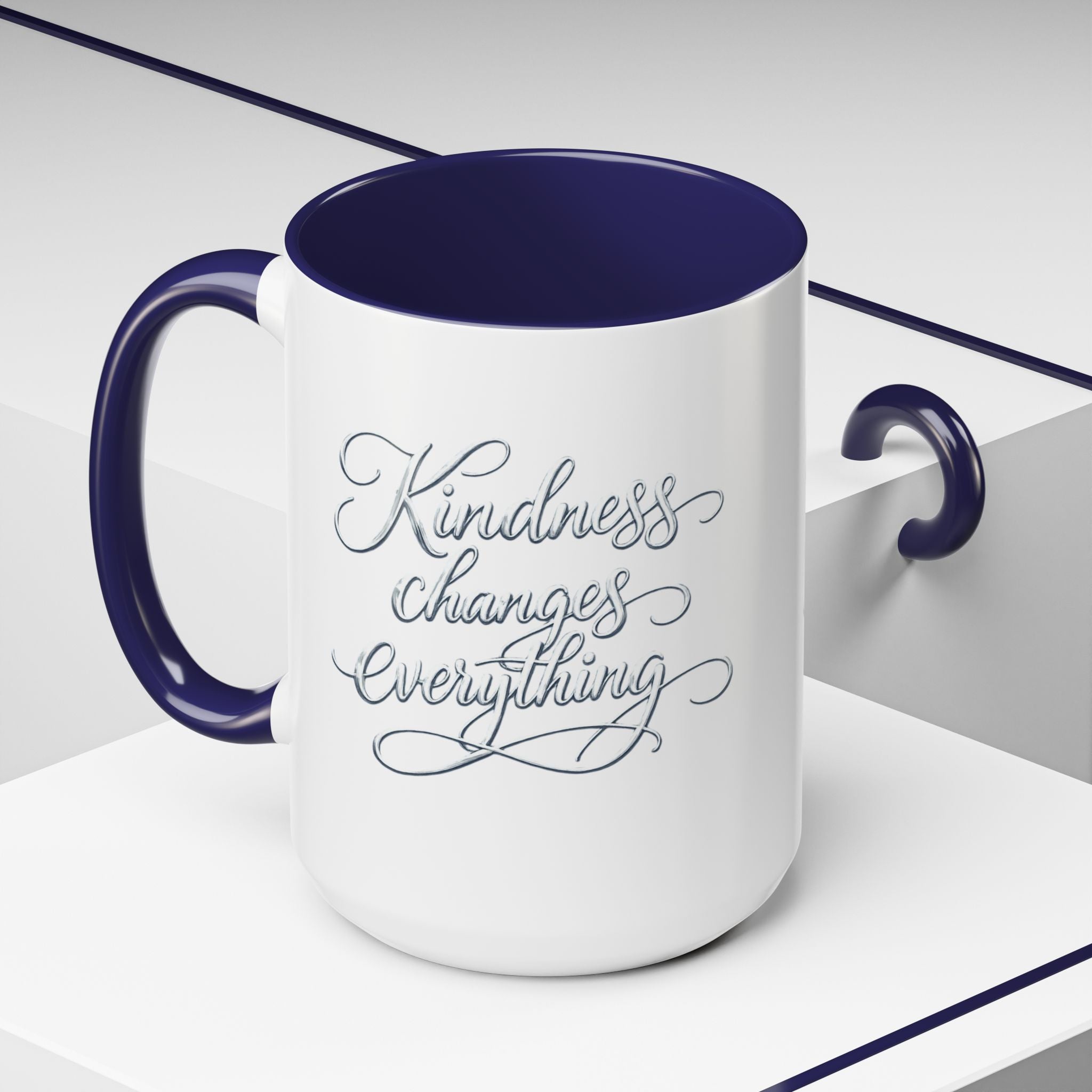 Inspirational ceramic accent coffee mug featuring elegant silver hand-lettered “Kindness Changes Everything” typography with colorful handle and interior accents.