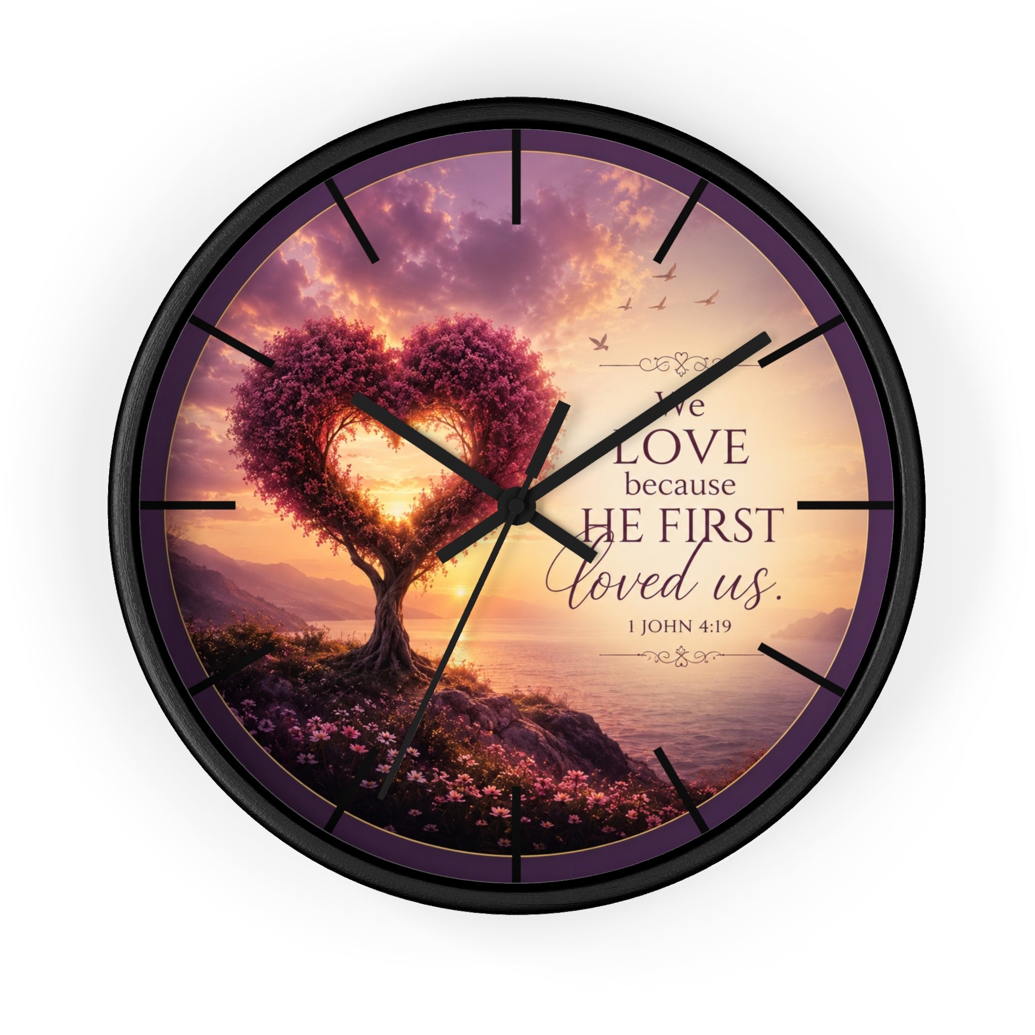 Inspirational Christian wall clock featuring a heart-shaped tree beside a peaceful shoreline sunset with 1 John 4:19 scripture about love and faith.
