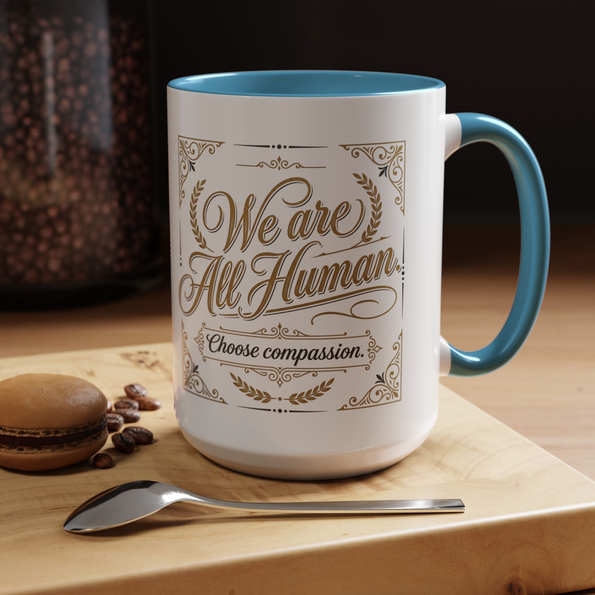 Inspirational ceramic accent coffee mug featuring “We Are All Human – Choose Compassion” in vintage-style gold lettering with decorative flourishes and black accent handle and interior.