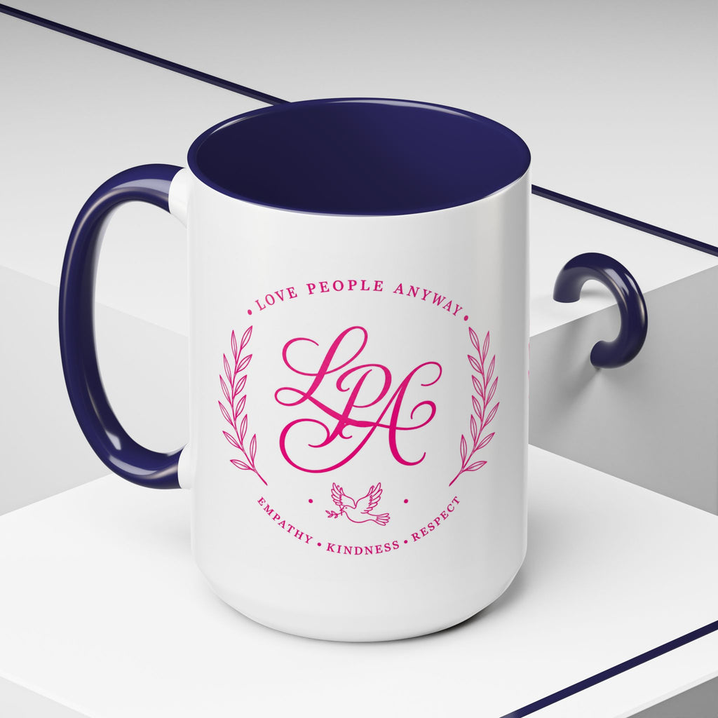 Inspirational ceramic coffee mug featuring soft pink “Love People Anyway” lettering, laurel accents, a dove motif, and contrasting blue handle and interior.