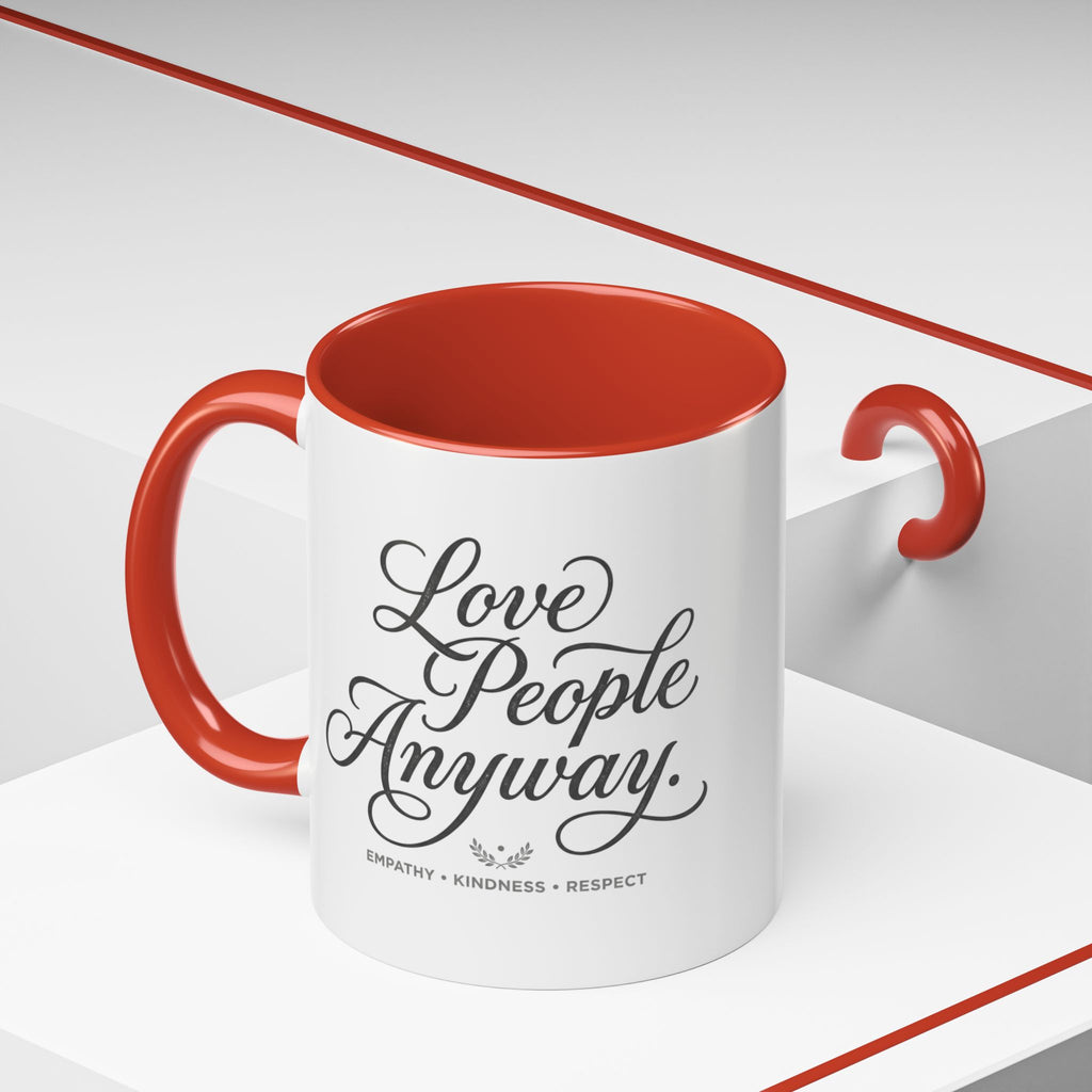 Inspirational ceramic accent coffee mug featuring hand-lettered “Love People Anyway” typography with empathy, kindness, and respect message on a glossy white mug with colorful handle and interior.