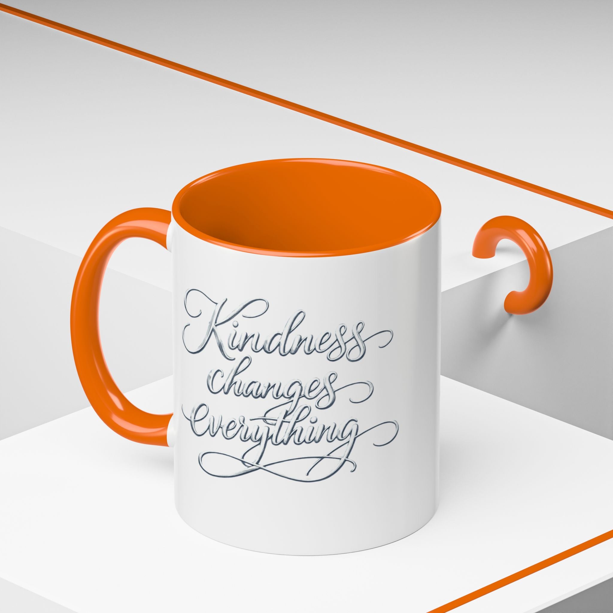 Inspirational ceramic accent coffee mug featuring elegant silver hand-lettered “Kindness Changes Everything” typography with colorful handle and interior accents.