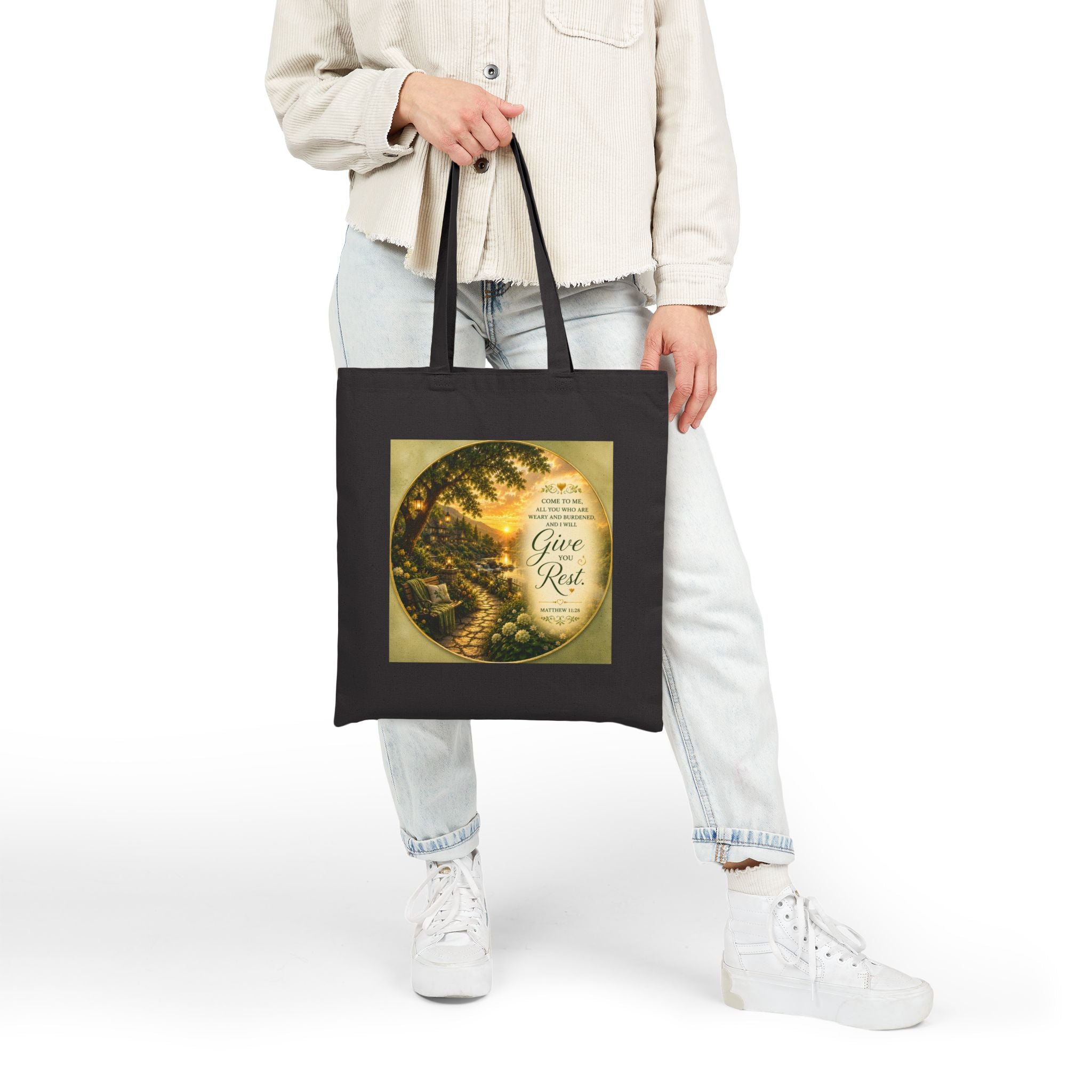 Christian cotton canvas tote bag featuring Matthew 11:28, “Come to Me, all you who are weary and burdened, and I will give you rest,” with peaceful garden pathway, glowing lanterns, riverside cottages, blooming flowers, and sunset artwork.