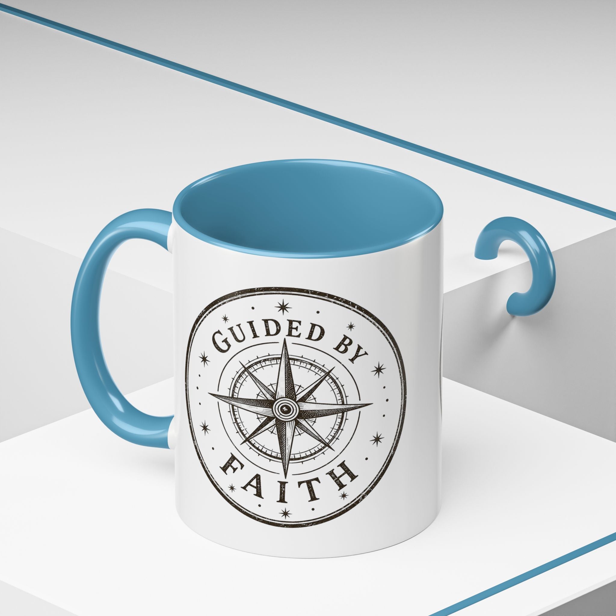 Inspirational ceramic accent coffee mug featuring a compass design and “Guided by Faith” message with colorful handle and interior accents on a glossy white mug.