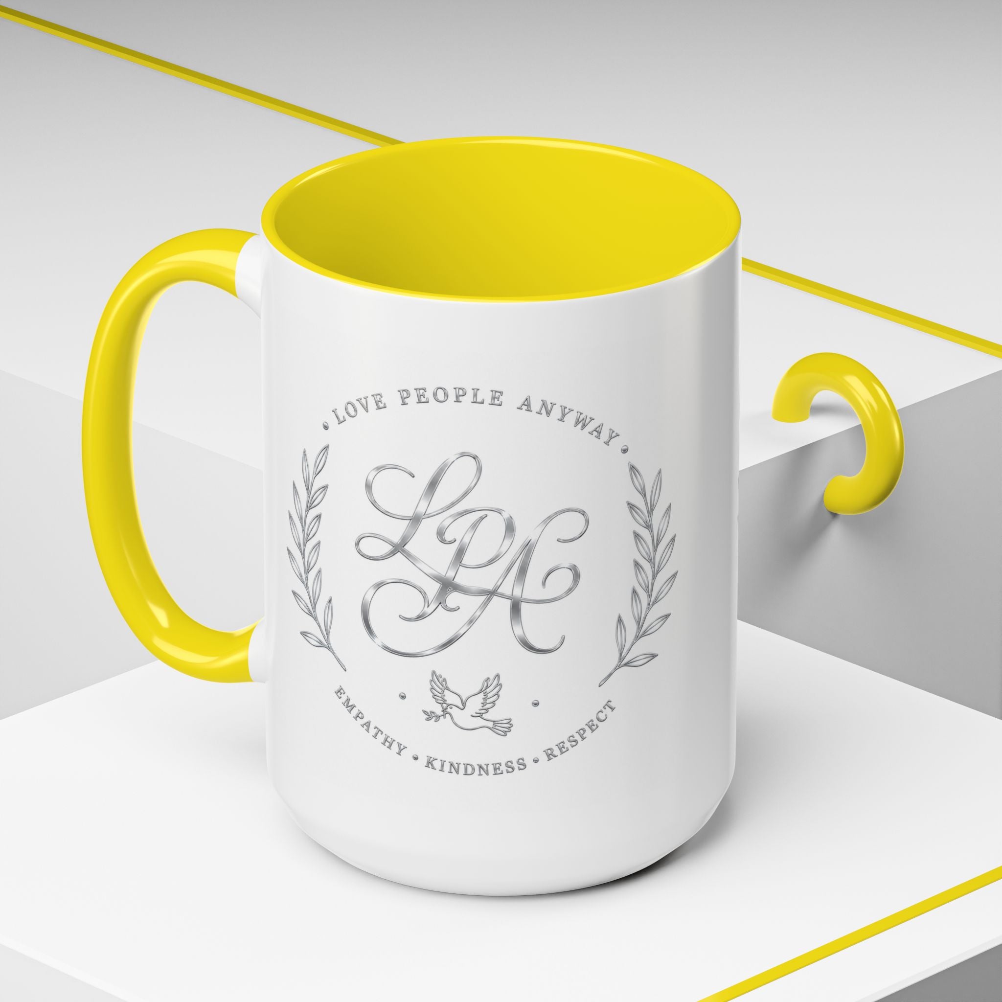 Inspirational ceramic coffee mug featuring silver “Love People Anyway” script, elegant monogram styling, decorative wreath accents, and contrasting handle and interior.