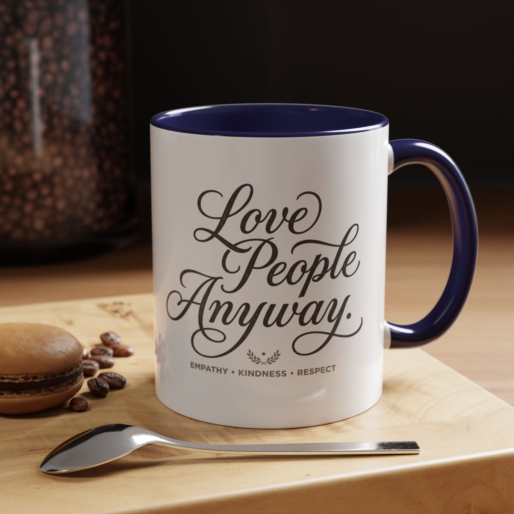 Inspirational ceramic accent coffee mug featuring hand-lettered “Love People Anyway” typography with empathy, kindness, and respect message on a glossy white mug with colorful handle and interior.