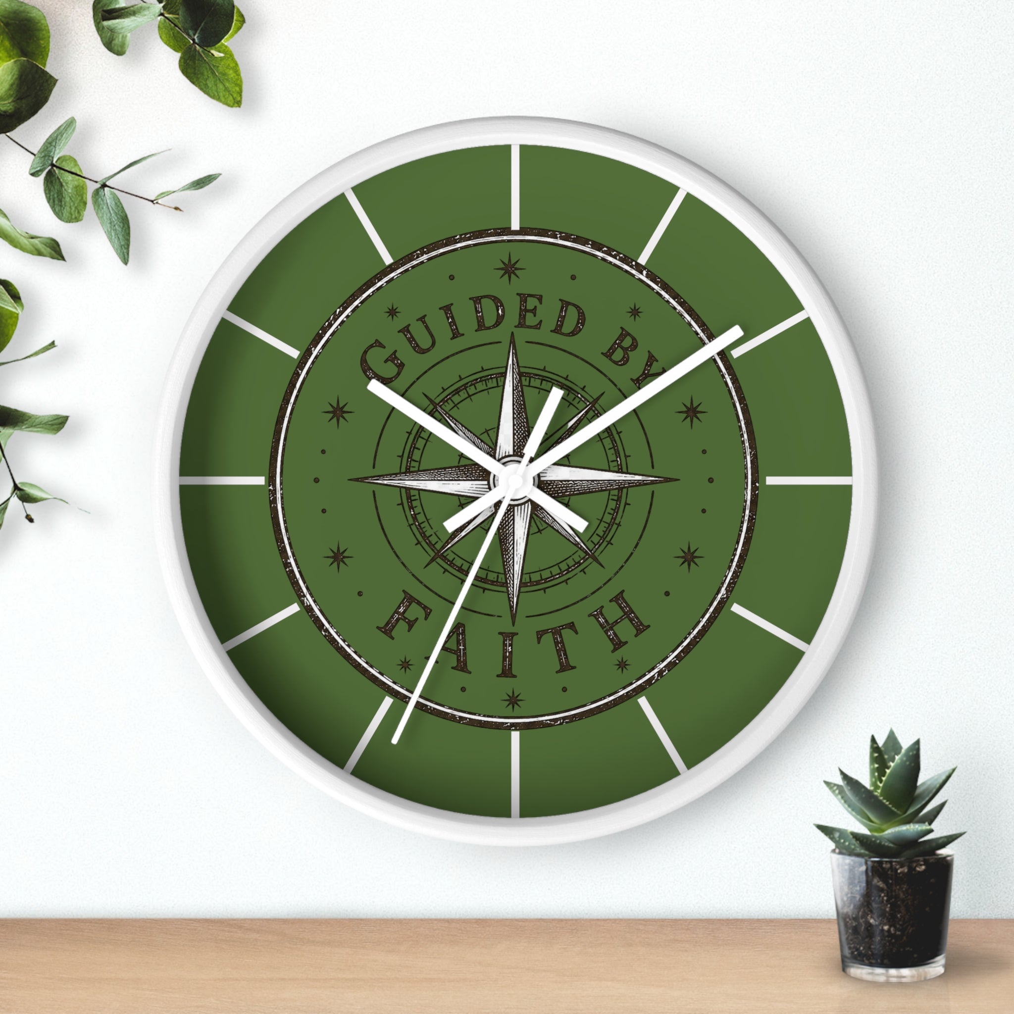 Rustic inspirational wall clock featuring a vintage compass design and the words “Guided by Faith” on an olive-green distressed background with silent movement.