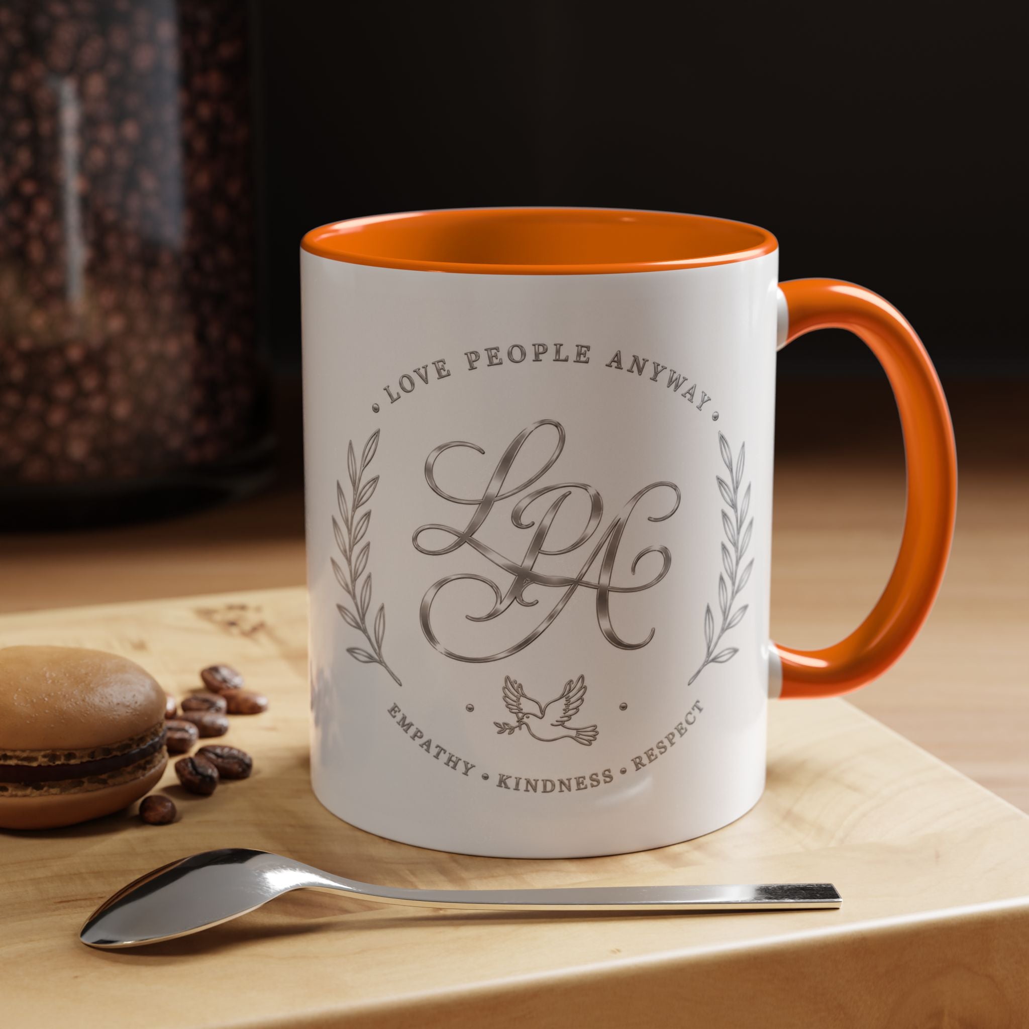 Inspirational ceramic coffee mug featuring silver “Love People Anyway” script, elegant monogram styling, decorative wreath accents, and contrasting handle and interior.