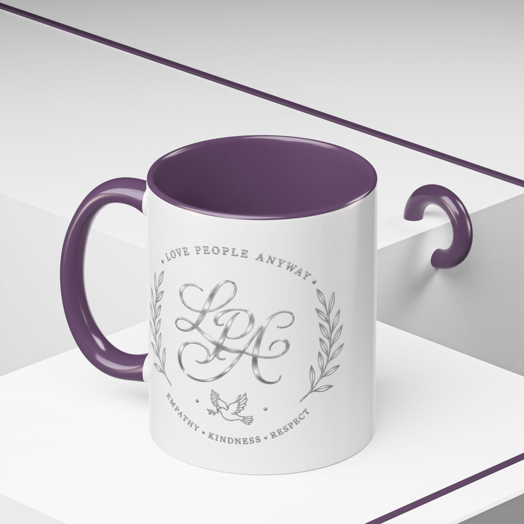 Inspirational ceramic coffee mug featuring silver “Love People Anyway” script, elegant monogram styling, decorative wreath accents, and contrasting handle and interior.