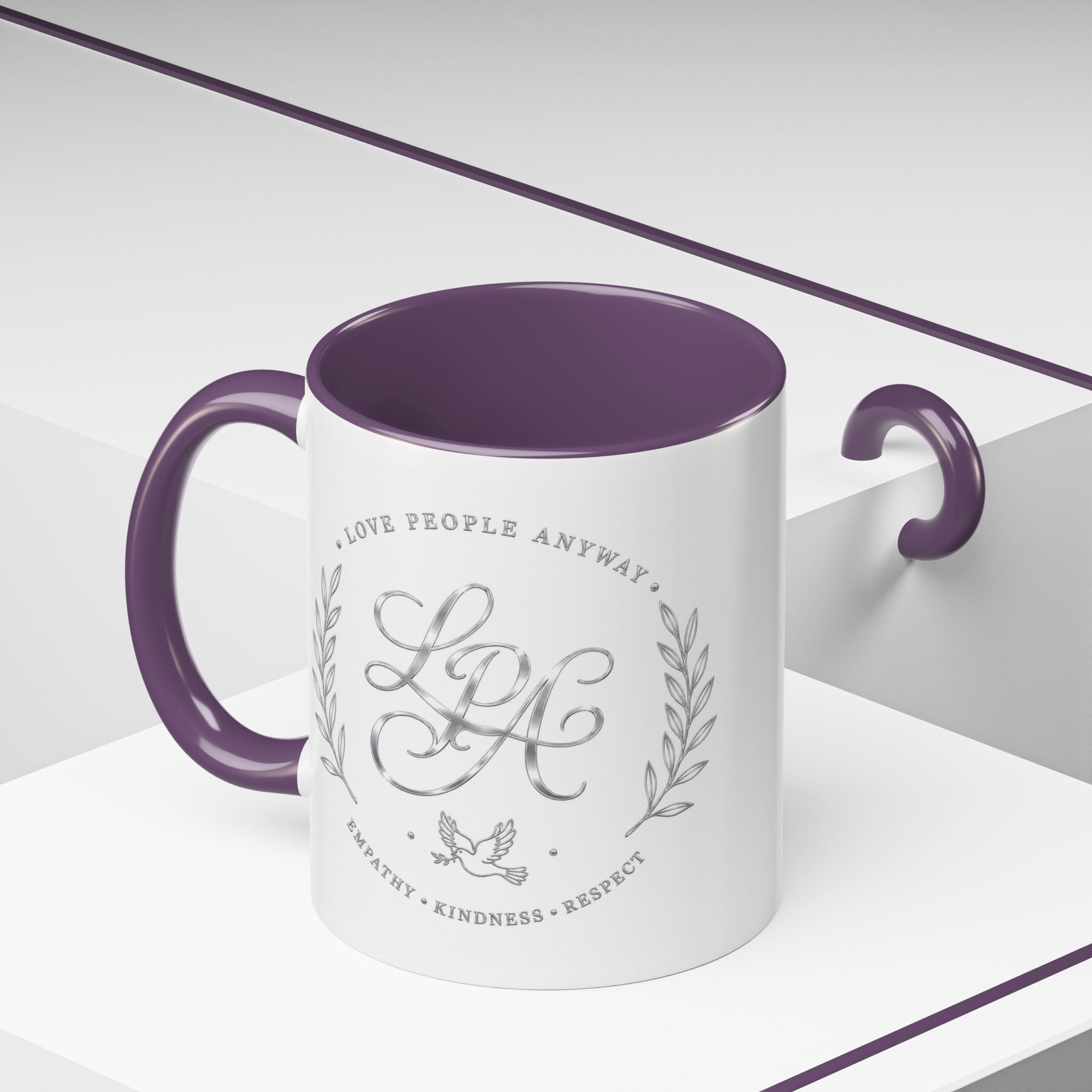 Inspirational ceramic coffee mug featuring silver “Love People Anyway” script, elegant monogram styling, decorative wreath accents, and contrasting handle and interior.