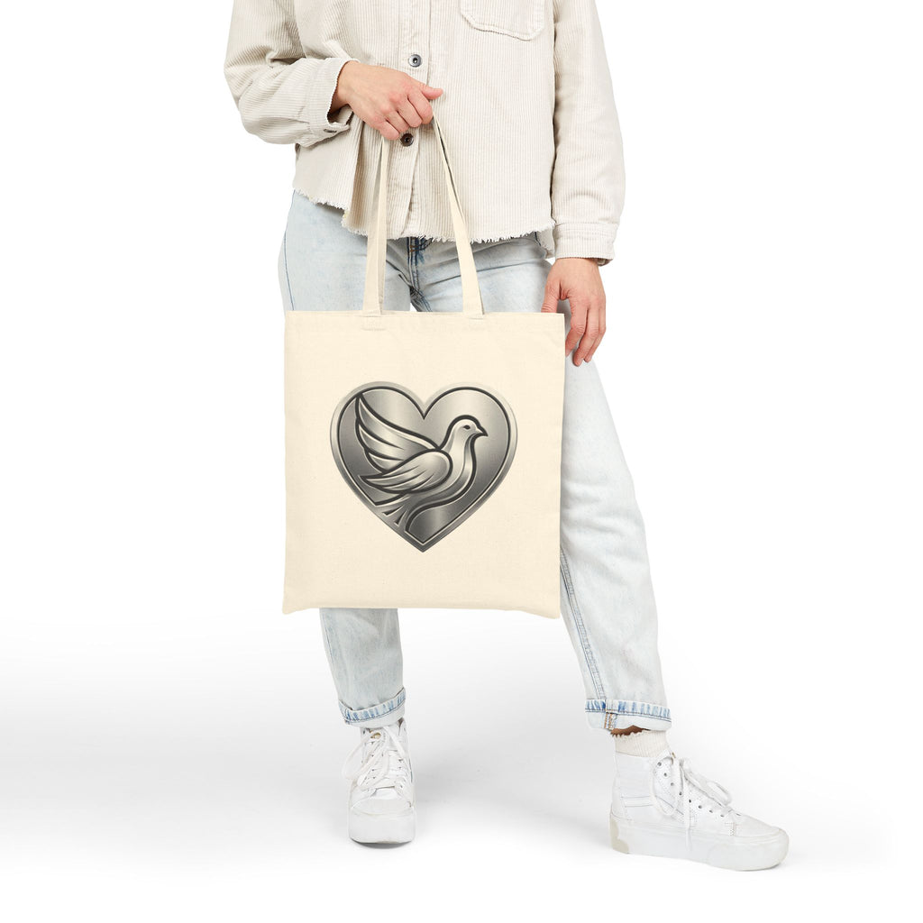 Cotton canvas tote bag featuring a silver dove inside a heart design, symbolizing peace, love, faith, hope, and encouragement in an elegant minimalist style.