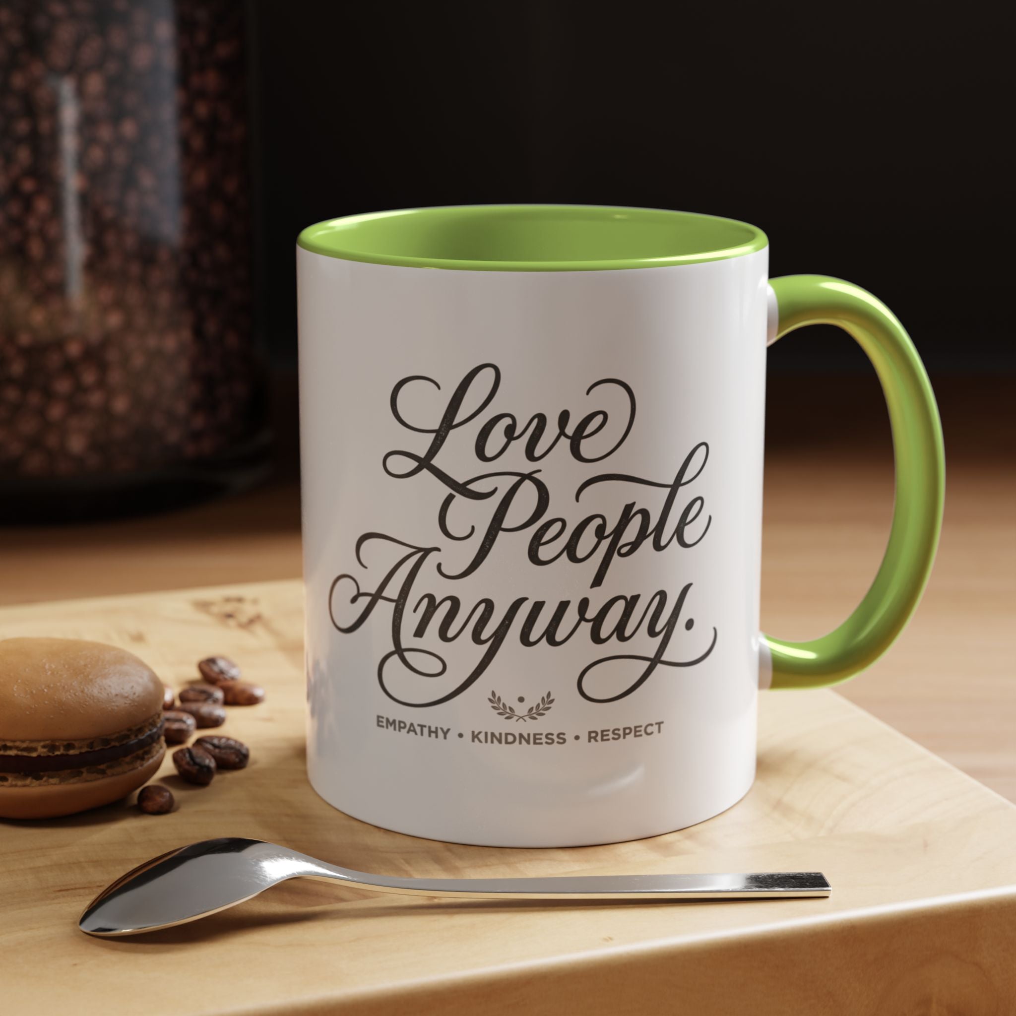 Inspirational ceramic accent coffee mug featuring hand-lettered “Love People Anyway” typography with empathy, kindness, and respect message on a glossy white mug with colorful handle and interior.