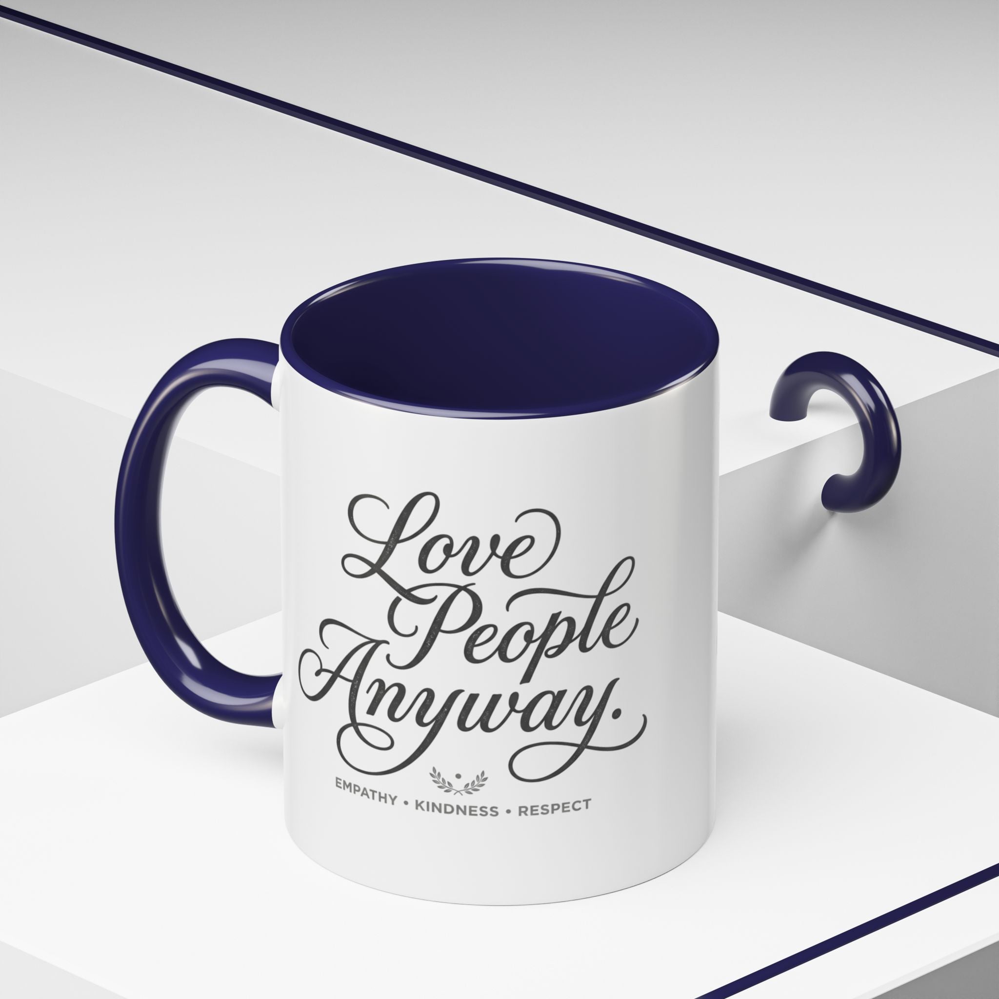 Inspirational ceramic accent coffee mug featuring hand-lettered “Love People Anyway” typography with empathy, kindness, and respect message on a glossy white mug with colorful handle and interior.