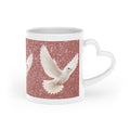 White ceramic heart-shaped handle mug featuring white doves flying across a shimmering rose gold sparkle background with vibrant wraparound artwork.
