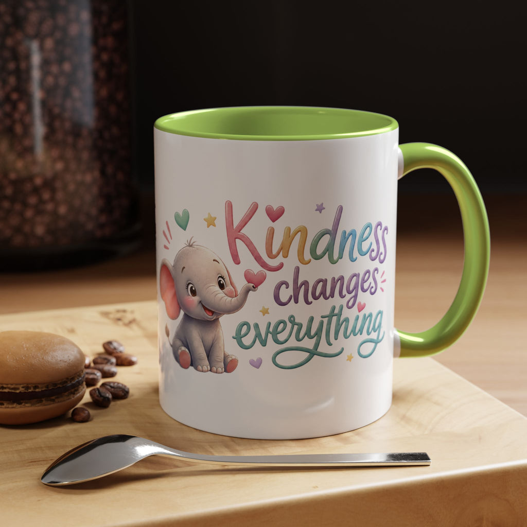 Cute ceramic coffee mug featuring a pastel baby elephant and the uplifting message “Kindness Changes Everything” with colorful accent handle and interior.