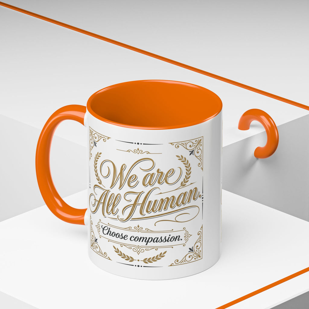 Inspirational ceramic accent coffee mug featuring “We Are All Human – Choose Compassion” in vintage-style gold lettering with decorative flourishes and black accent handle and interior.