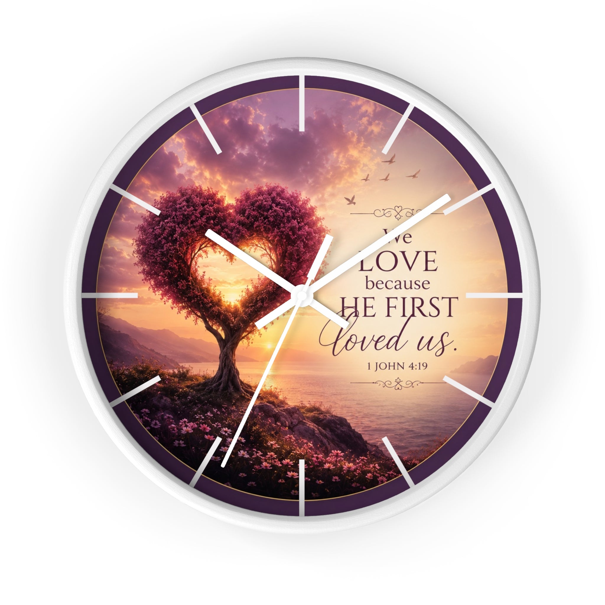 Inspirational Christian wall clock featuring a heart-shaped tree beside a peaceful shoreline sunset with 1 John 4:19 scripture about love and faith.