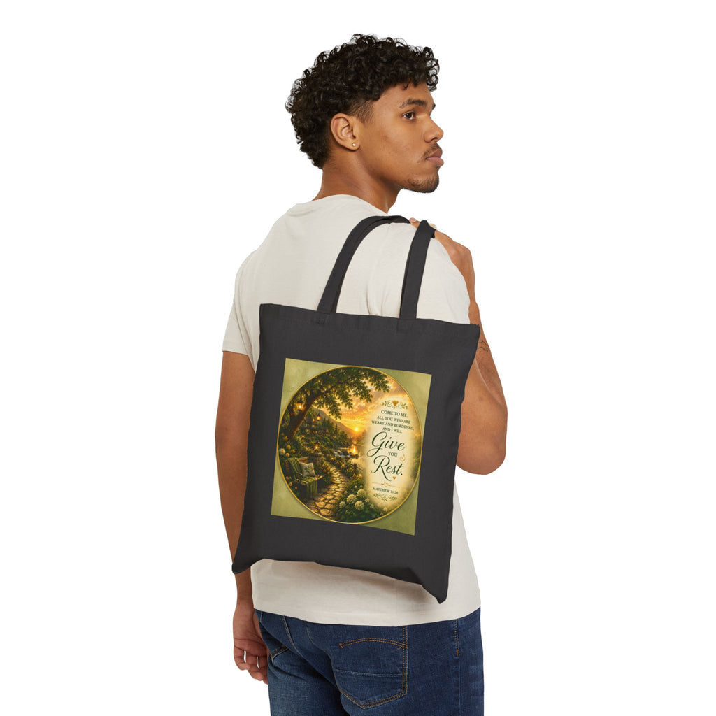 Christian cotton canvas tote bag featuring Matthew 11:28, “Come to Me, all you who are weary and burdened, and I will give you rest,” with peaceful garden pathway, glowing lanterns, riverside cottages, blooming flowers, and sunset artwork.