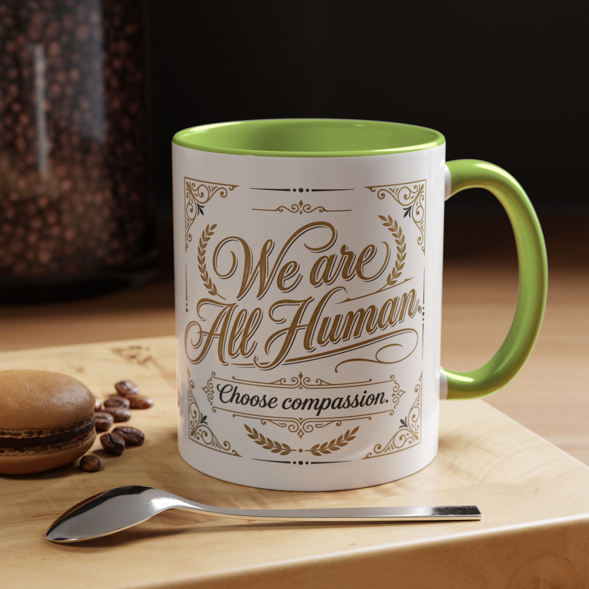 Inspirational ceramic accent coffee mug featuring “We Are All Human – Choose Compassion” in vintage-style gold lettering with decorative flourishes and black accent handle and interior.