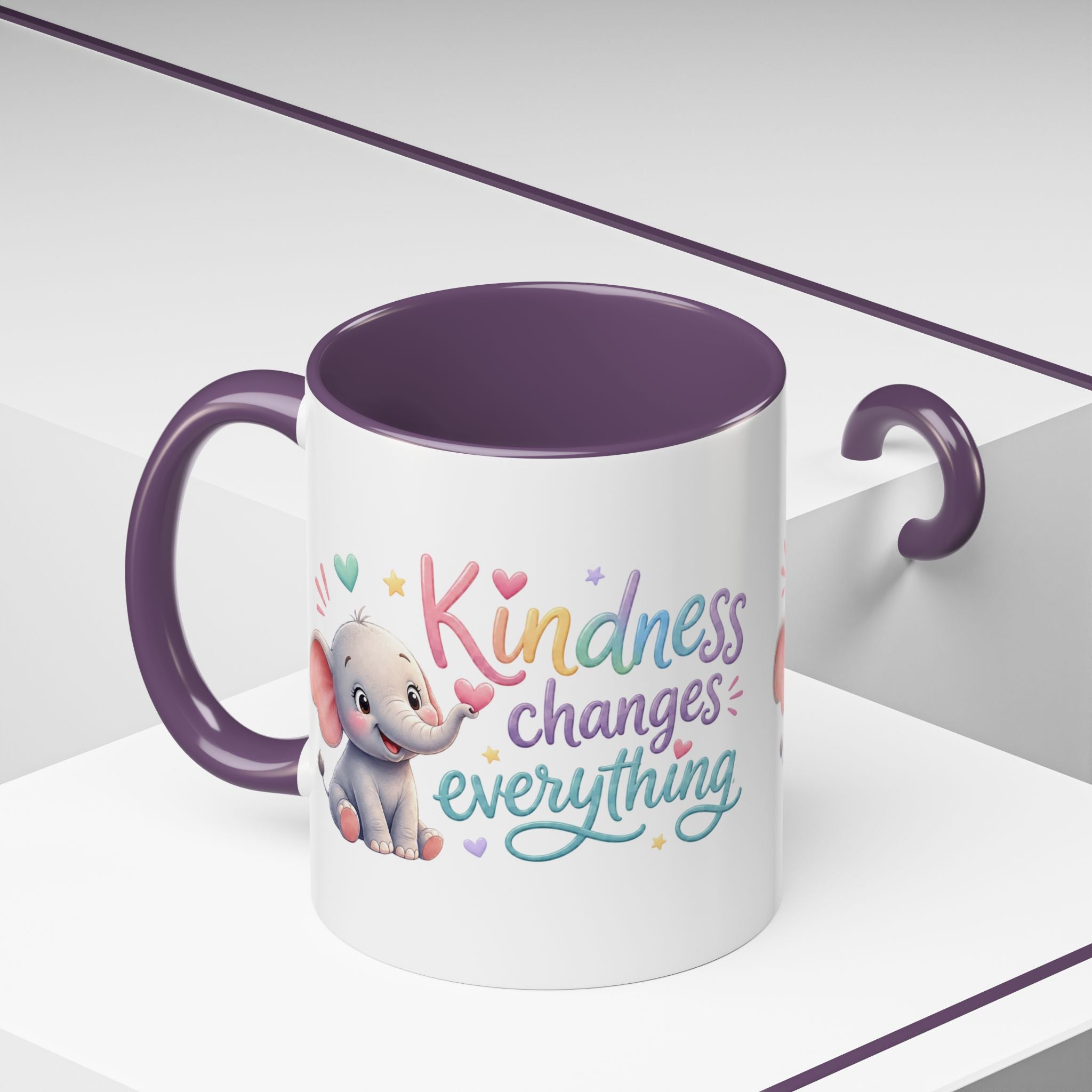 Cute ceramic coffee mug featuring a pastel baby elephant and the uplifting message “Kindness Changes Everything” with colorful accent handle and interior.
