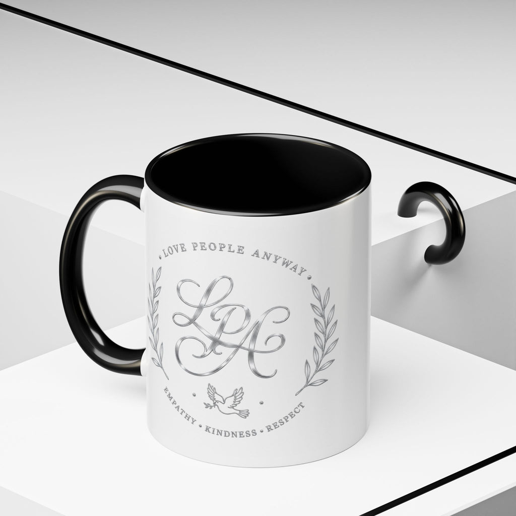 Inspirational ceramic coffee mug featuring silver “Love People Anyway” script, elegant monogram styling, decorative wreath accents, and contrasting handle and interior.