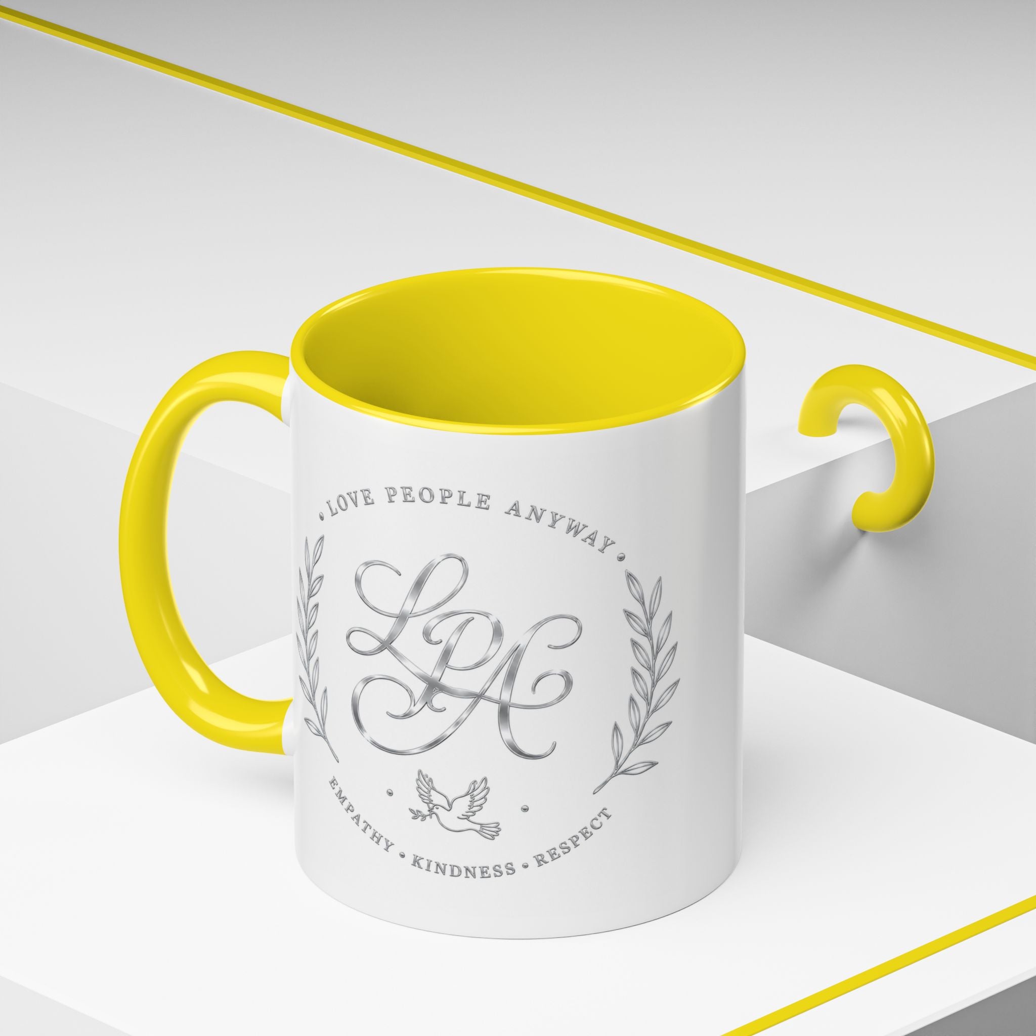 Inspirational ceramic coffee mug featuring silver “Love People Anyway” script, elegant monogram styling, decorative wreath accents, and contrasting handle and interior.