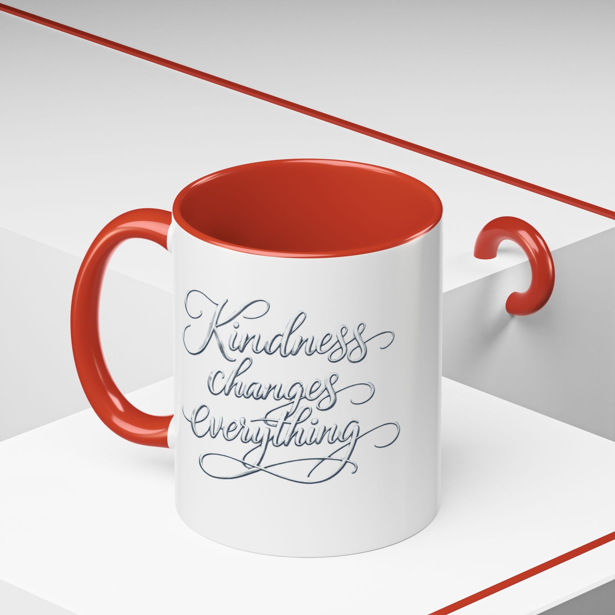 Inspirational ceramic accent coffee mug featuring elegant silver hand-lettered “Kindness Changes Everything” typography with colorful handle and interior accents.