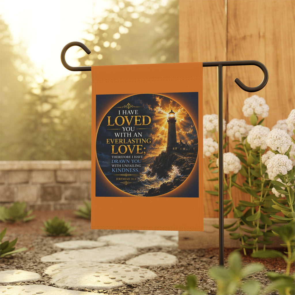 Inspirational Christian garden flag featuring a glowing lighthouse beneath stormy skies with Jeremiah 31:3 everlasting love scripture artwork in coastal-inspired tones.