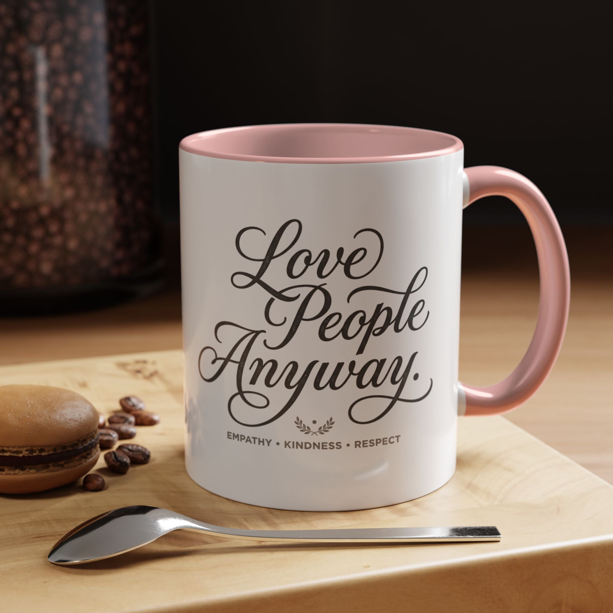 Inspirational ceramic accent coffee mug featuring hand-lettered “Love People Anyway” typography with empathy, kindness, and respect message on a glossy white mug with colorful handle and interior.