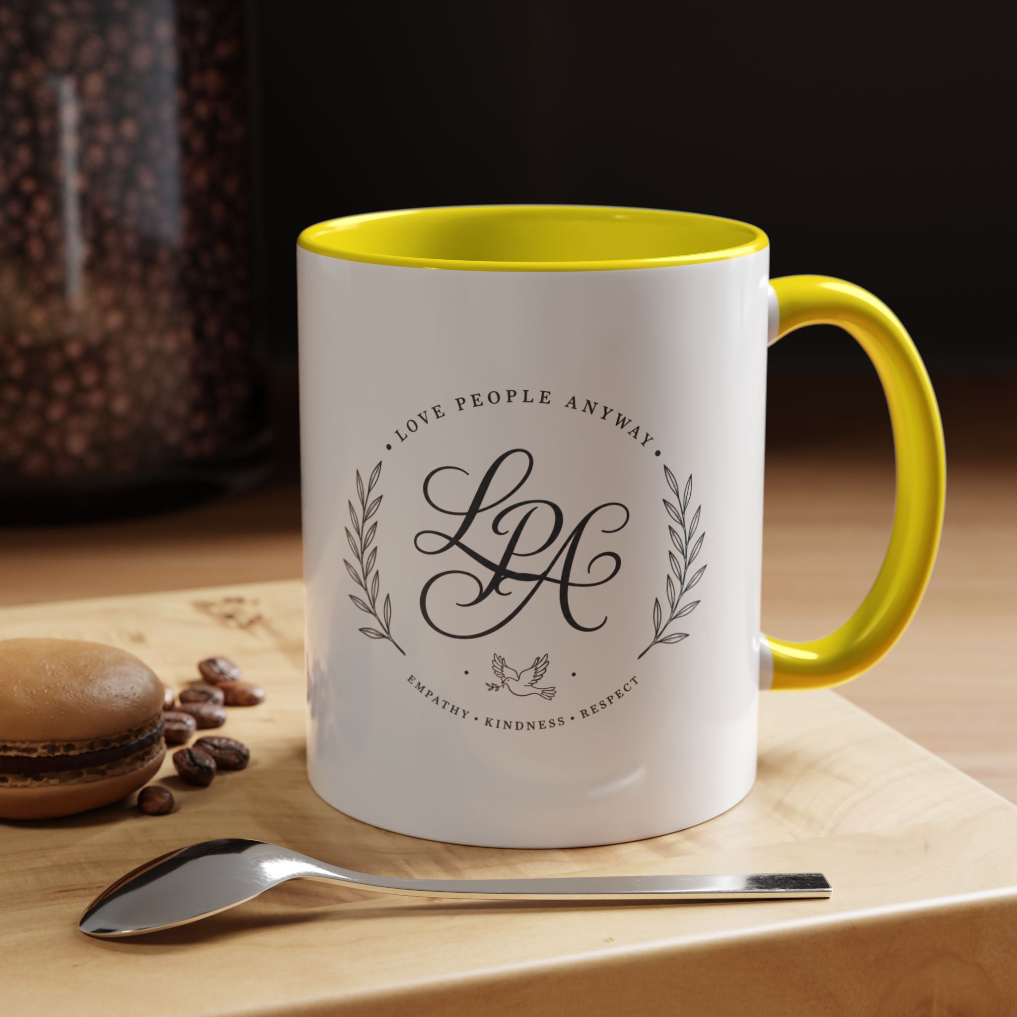 Personalized ceramic accent coffee mug featuring a custom monogram crest and the inspirational message “Love People Anyway” with colorful handle and interior accents.
