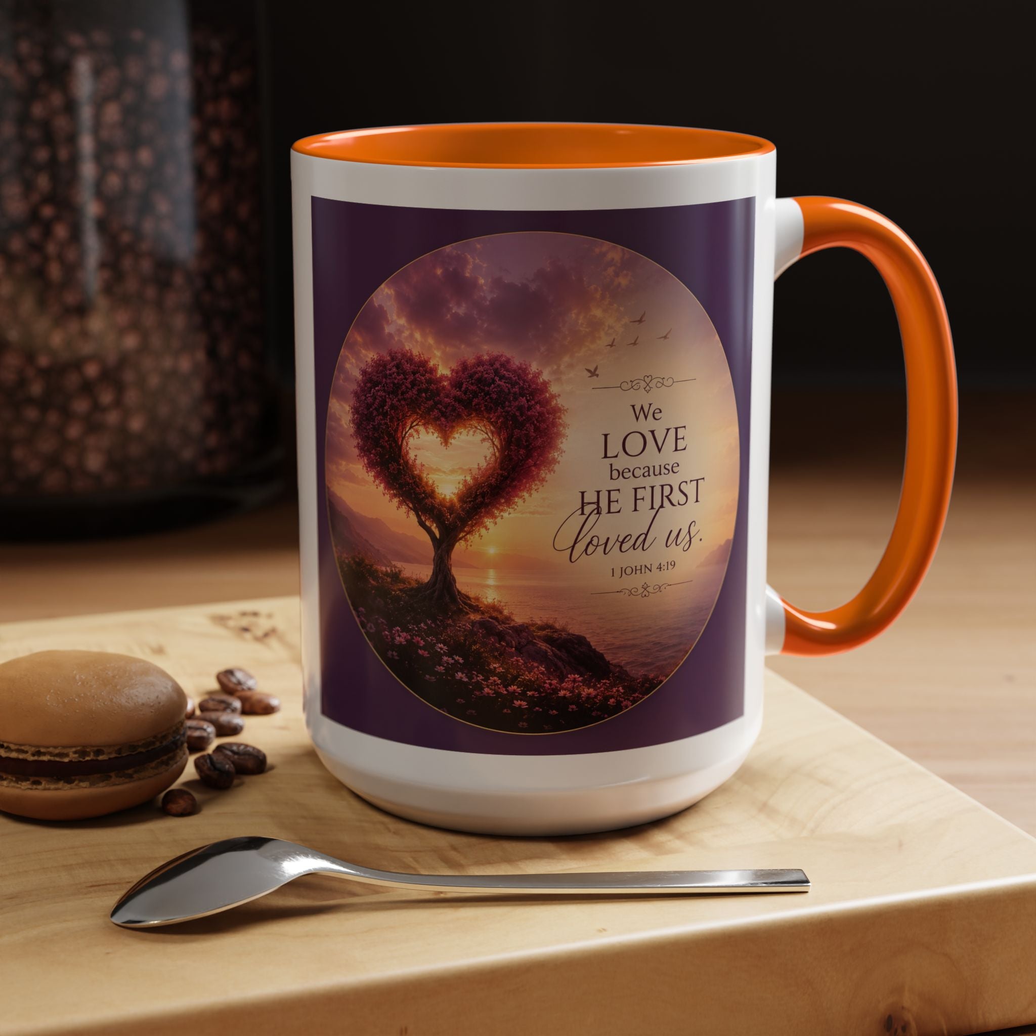 Inspirational Christian coffee mug featuring a glowing heart-shaped tree at sunset with the scripture “We Love Because He First Loved Us” from 1 John 4:19 and contrasting black handle and interior.