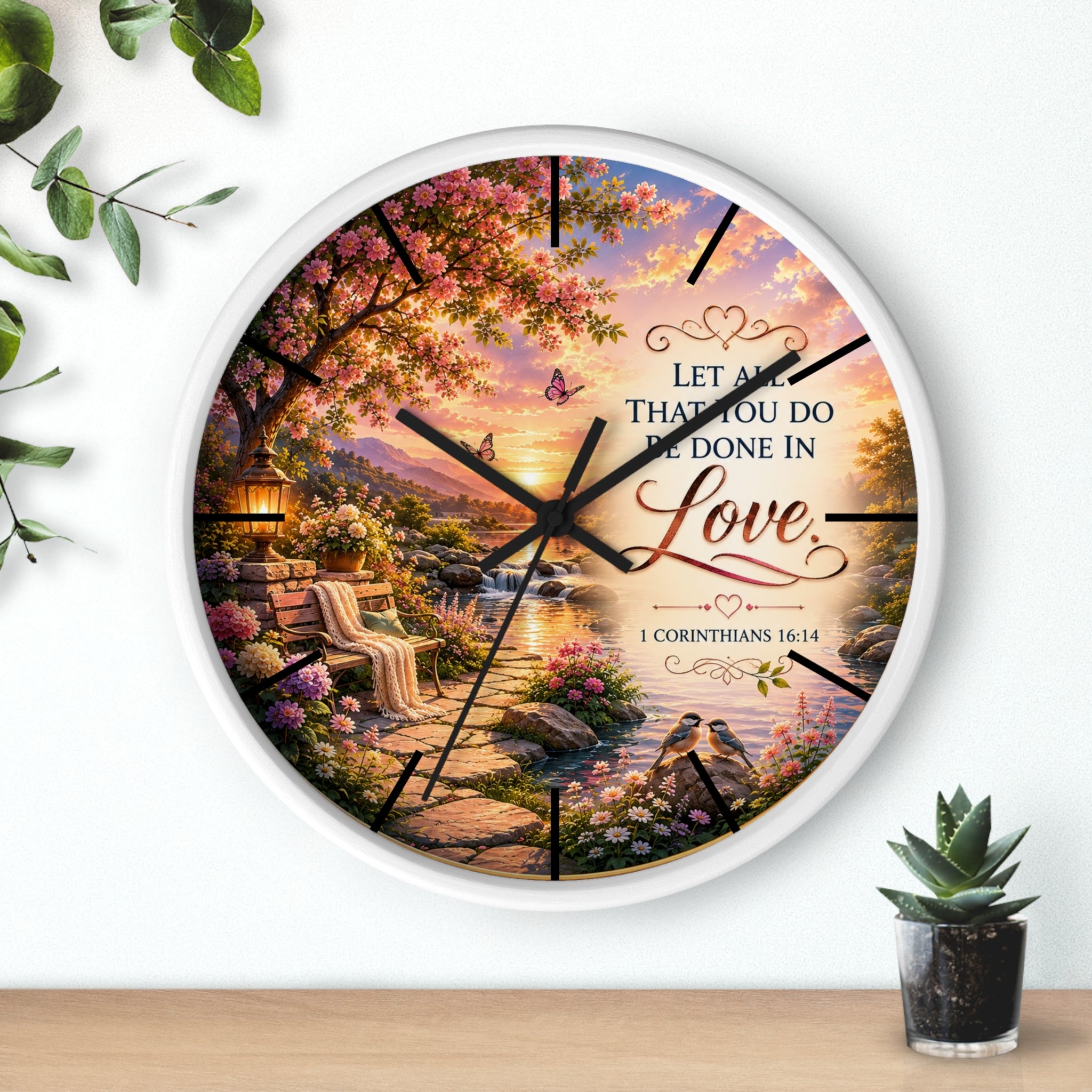 Inspirational Christian wall clock featuring a flower-lined lakeside sunrise scene with 1 Corinthians 16:14 scripture about doing all things in love.