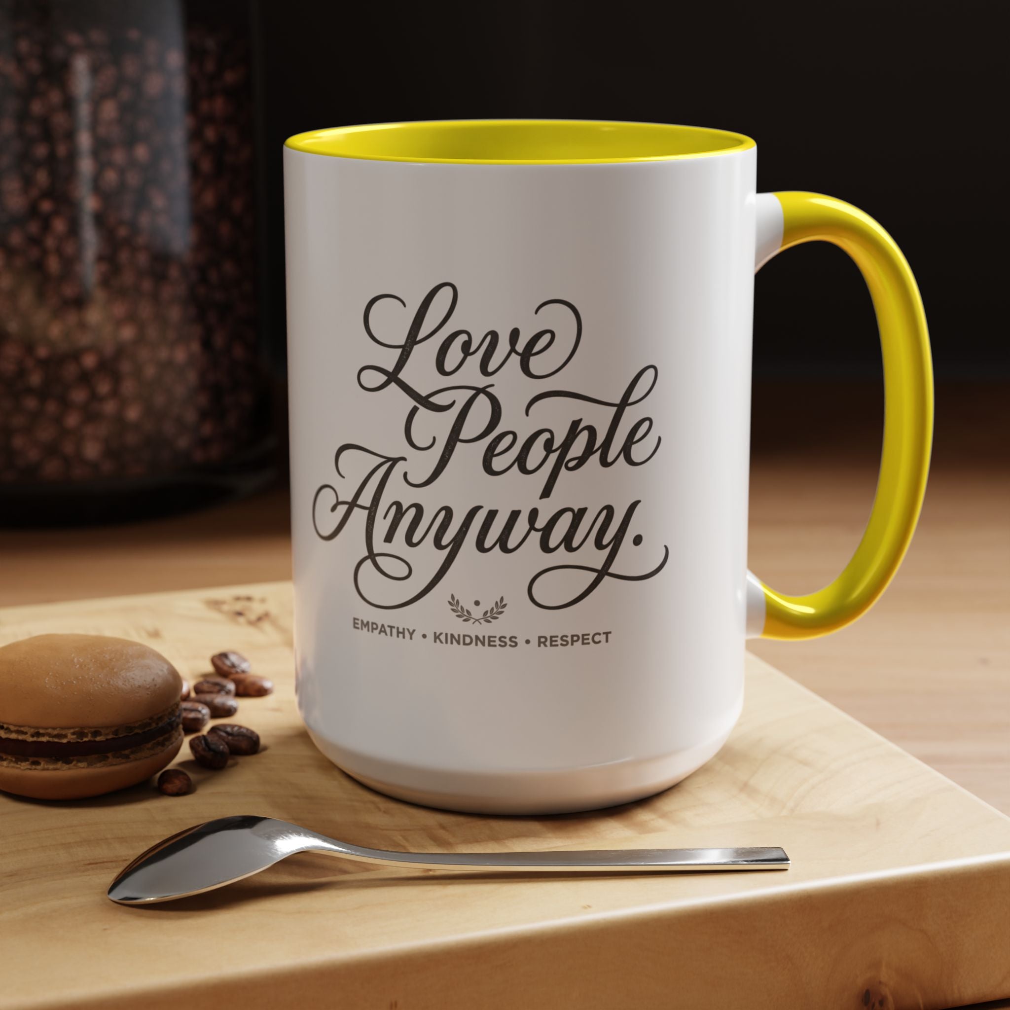 Inspirational ceramic accent coffee mug featuring hand-lettered “Love People Anyway” typography with empathy, kindness, and respect message on a glossy white mug with colorful handle and interior.