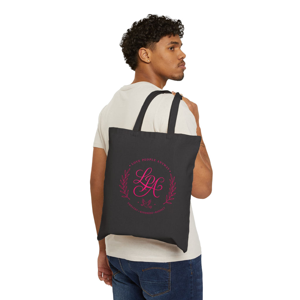 Pink monogram cotton canvas tote bag featuring the message “Love People Anyway,” laurel branches, a dove carrying an olive branch, and the words empathy, kindness, and respect in an elegant boutique design.