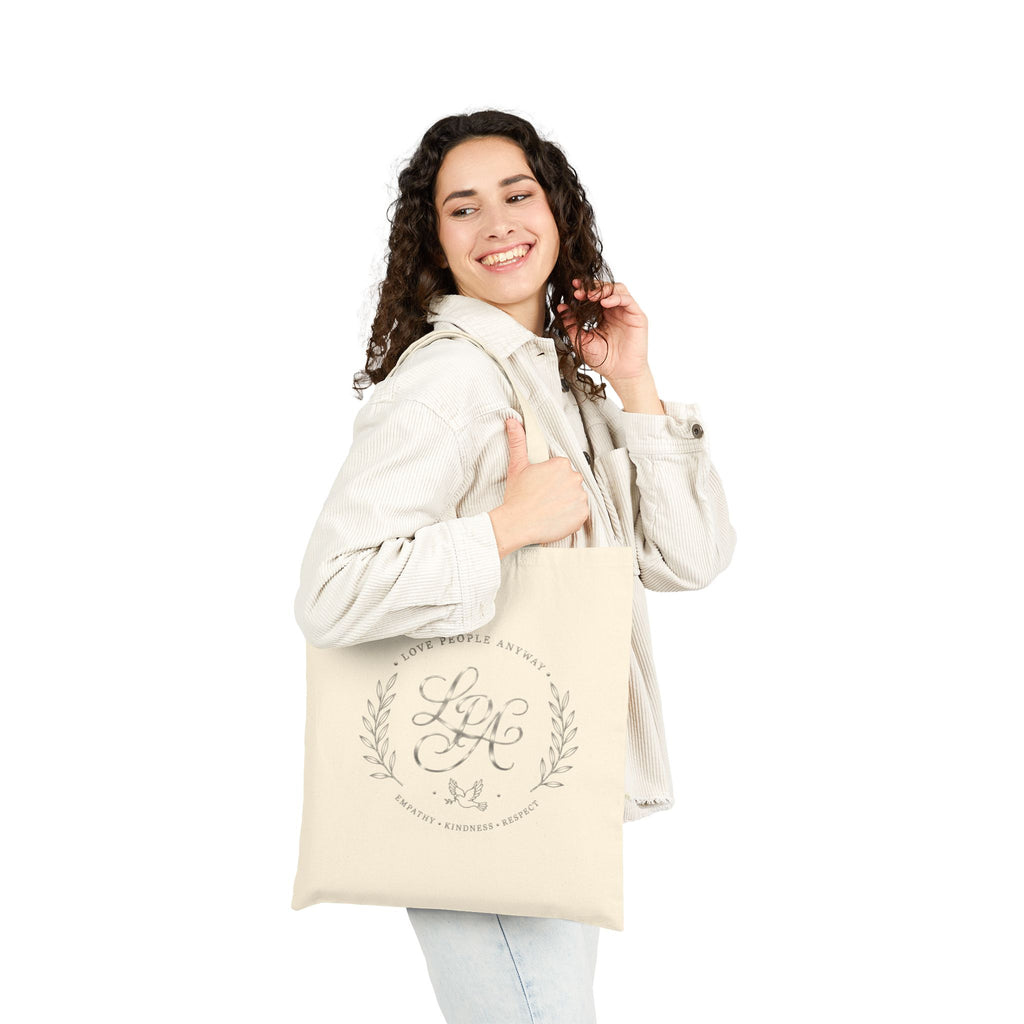 Elegant cotton canvas tote bag featuring a silver monogram crest, laurel branches, dove with olive branch, and the message “Love People Anyway” with empathy, kindness, and respect accents.