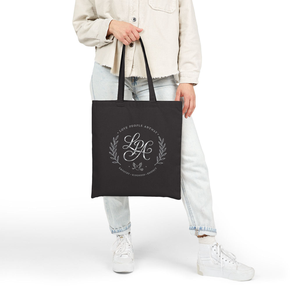 Elegant cotton canvas tote bag featuring a silver monogram crest, laurel branches, dove with olive branch, and the message “Love People Anyway” with empathy, kindness, and respect accents.