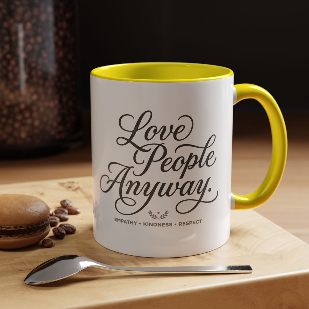 Inspirational ceramic accent coffee mug featuring hand-lettered “Love People Anyway” typography with empathy, kindness, and respect message on a glossy white mug with colorful handle and interior.