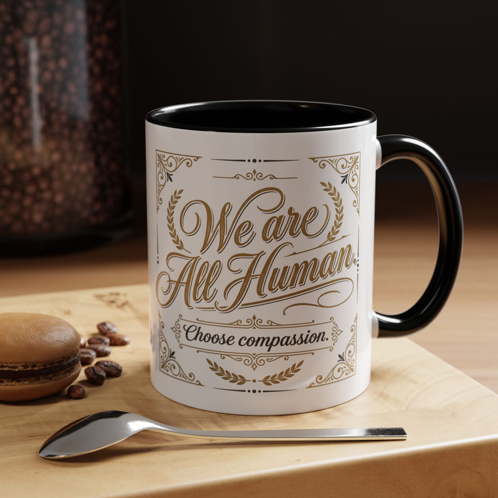 Inspirational ceramic accent coffee mug featuring “We Are All Human – Choose Compassion” in vintage-style gold lettering with decorative flourishes and black accent handle and interior.