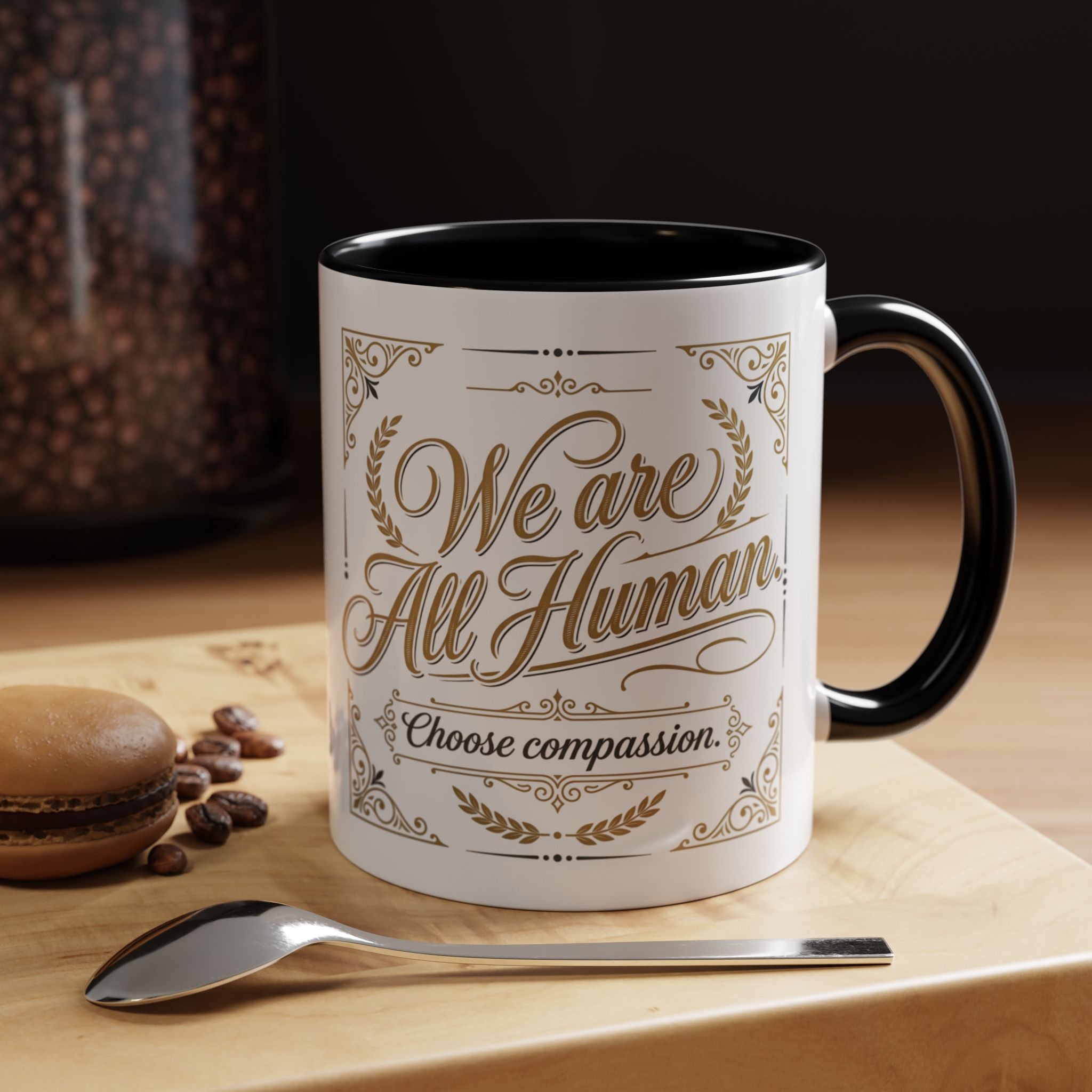 Inspirational ceramic accent coffee mug featuring “We Are All Human – Choose Compassion” in vintage-style gold lettering with decorative flourishes and black accent handle and interior.