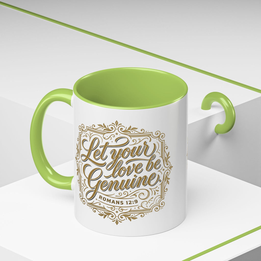 Inspirational ceramic accent coffee mug featuring Romans 12:9 and the message “Let Your Love Be Genuine” in elegant gold script with decorative flourishes and black accent handle and interior.