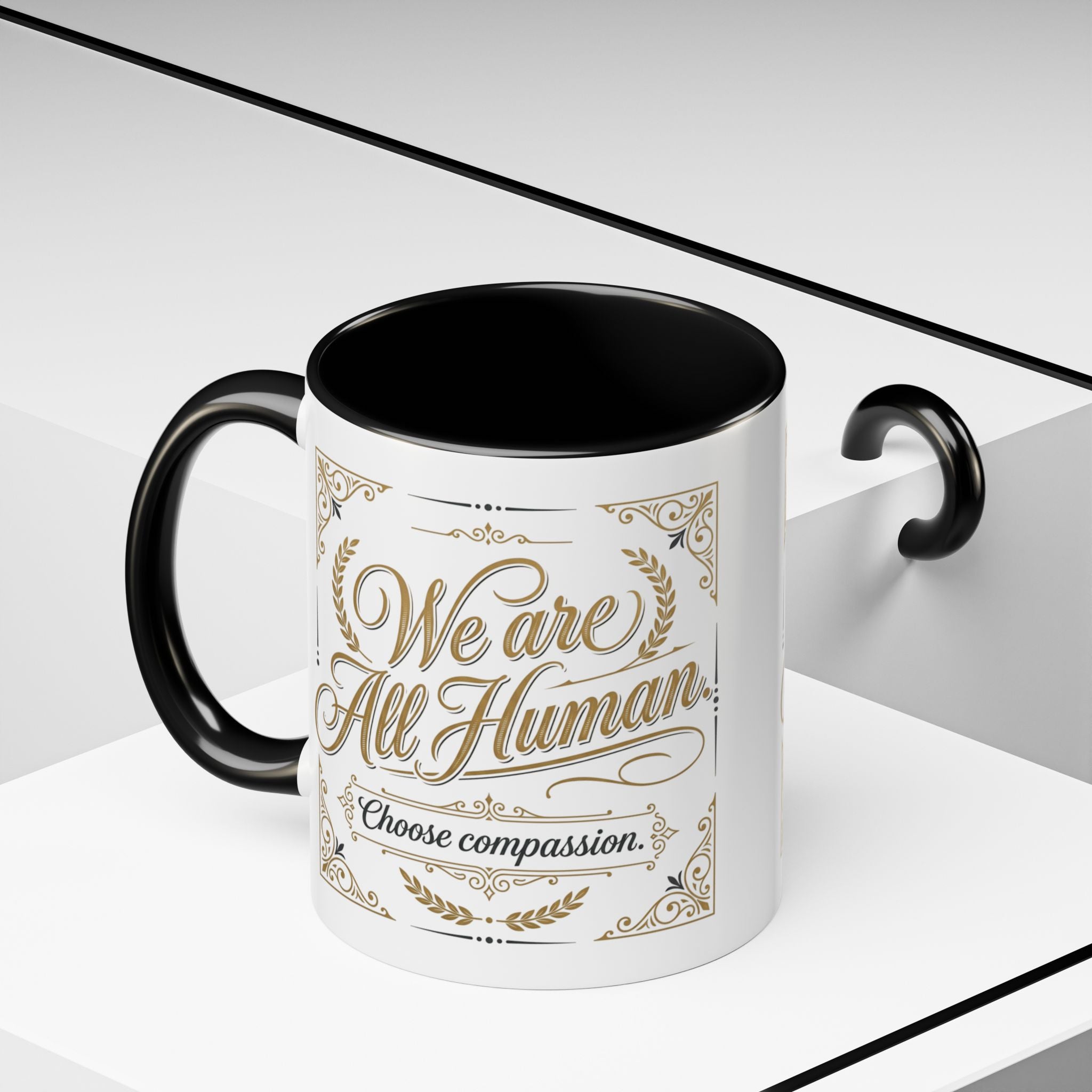 Inspirational ceramic accent coffee mug featuring “We Are All Human – Choose Compassion” in vintage-style gold lettering with decorative flourishes and black accent handle and interior.