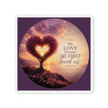 Die-cut Christian magnet featuring a heart-shaped tree at sunset with the scripture “We Love Because He First Loved Us” from 1 John 4:19 in purple, pink, and gold tones overlooking a peaceful shoreline.