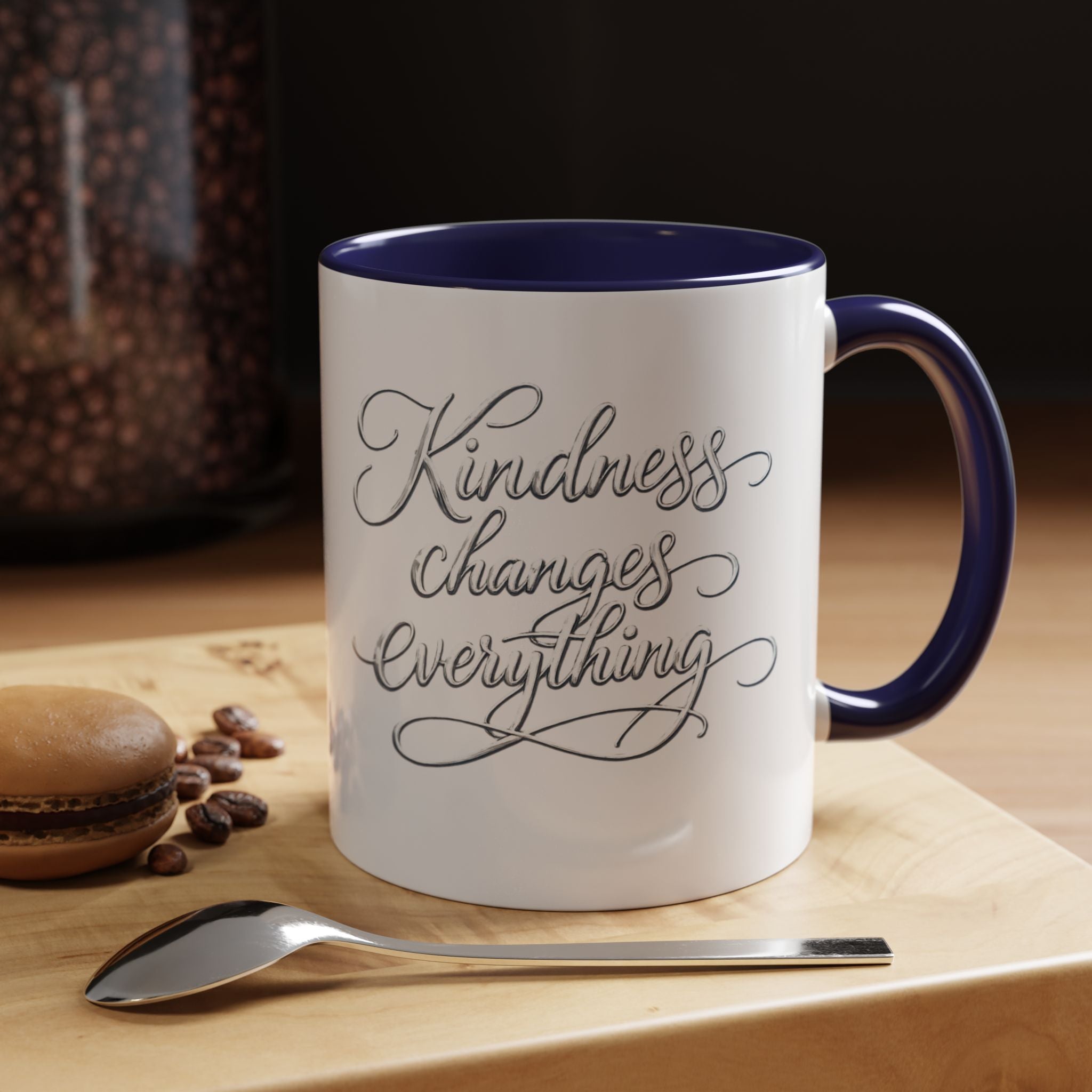 Inspirational ceramic accent coffee mug featuring elegant silver hand-lettered “Kindness Changes Everything” typography with colorful handle and interior accents.