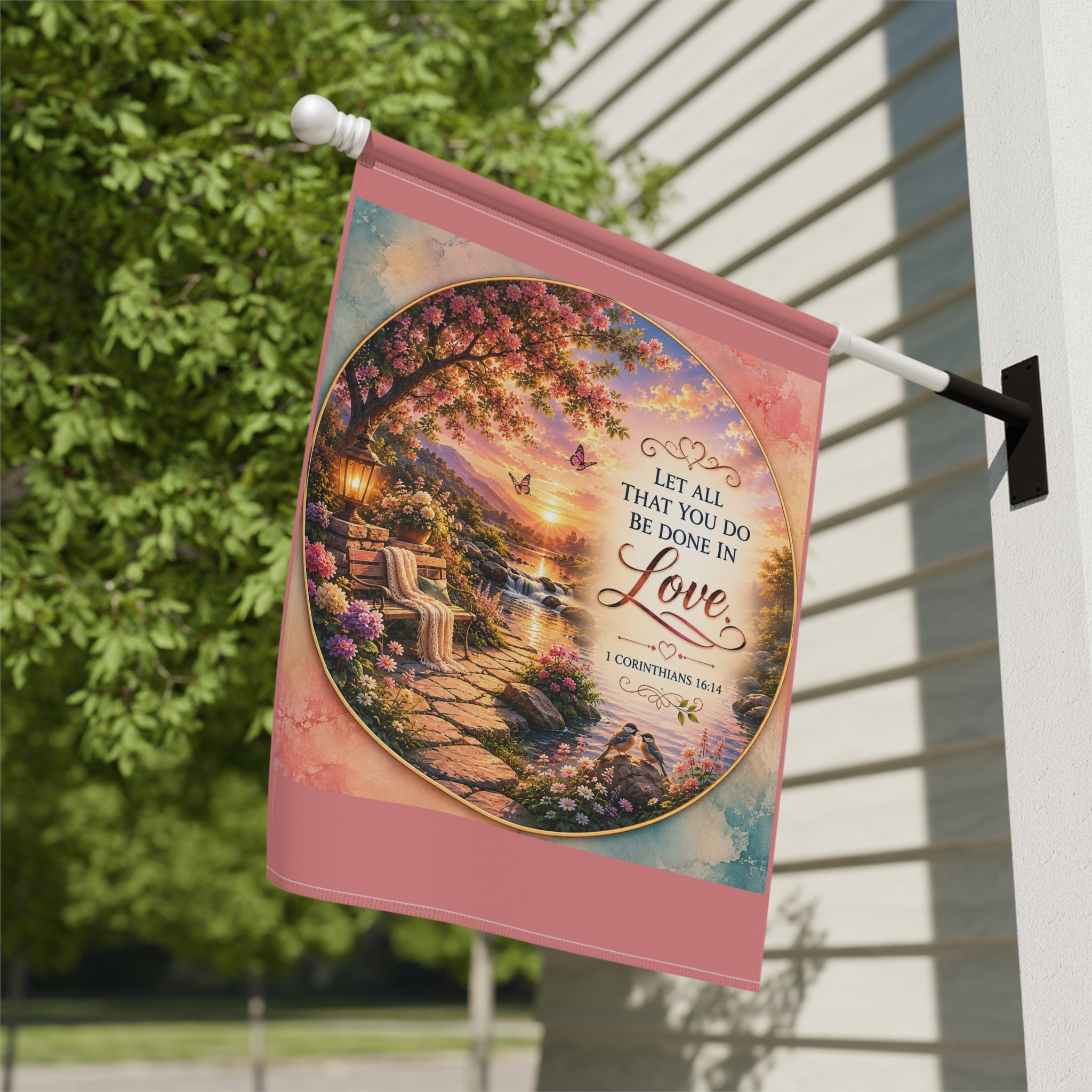 Inspirational Christian garden flag featuring a floral lakeside scene with hydrangeas, a sunlit pathway, and 1 Corinthians 16:14 scripture about love.
